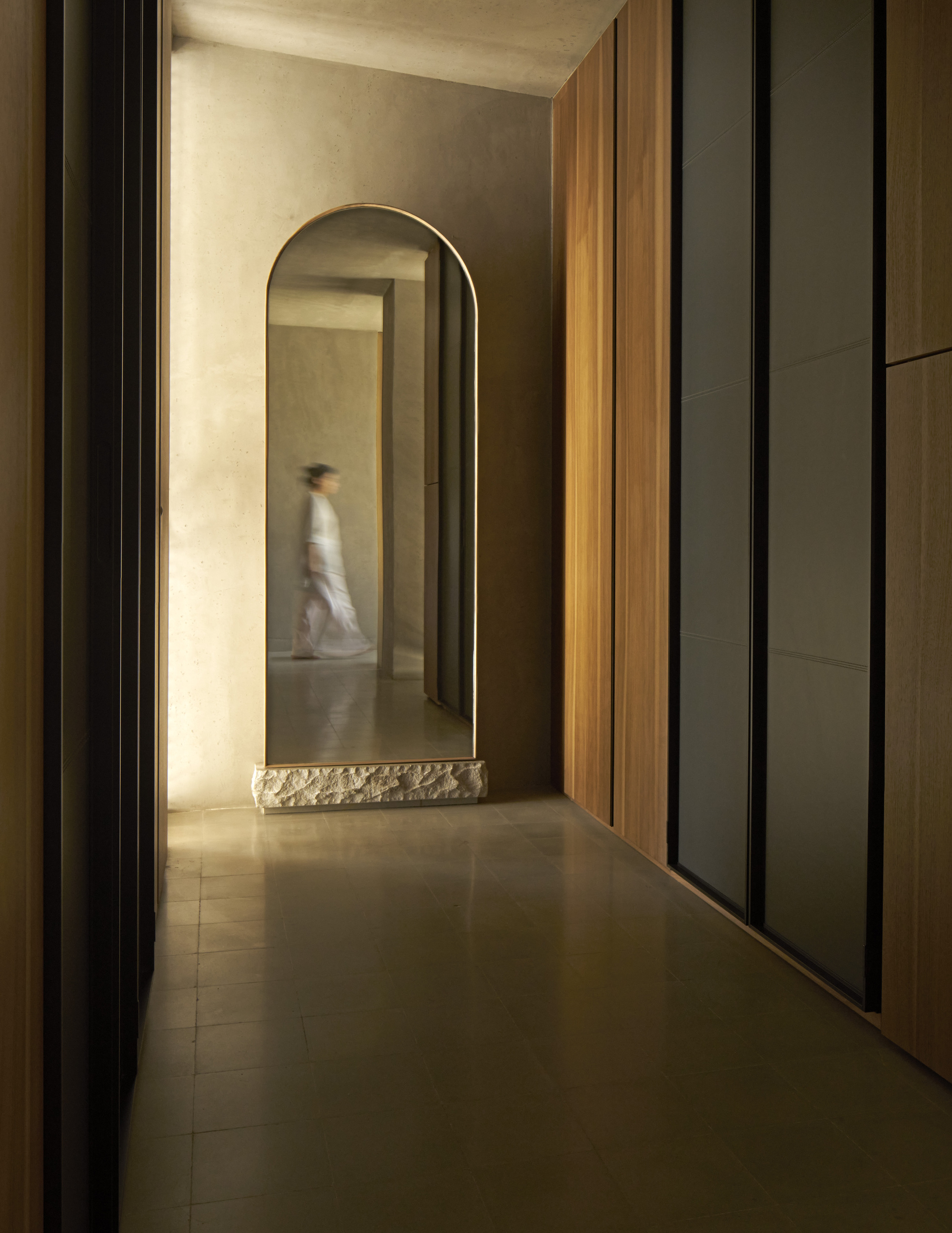 Corridor with arched opening, timber paneling and a figure passing through in motion blur