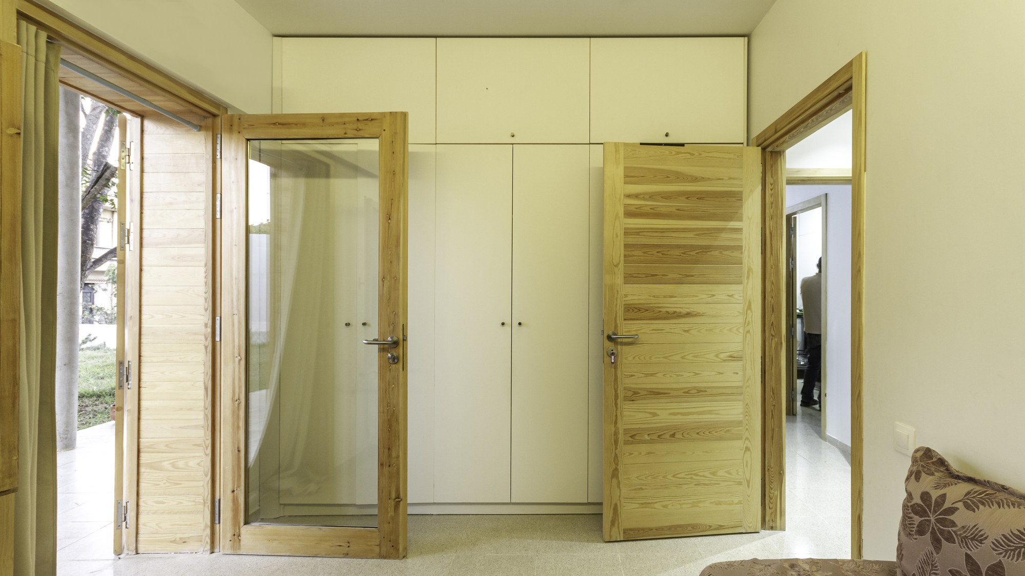 Interior bedroom corner with timber-framed louvered doors and white built-in wardrobes flanking timber panel door