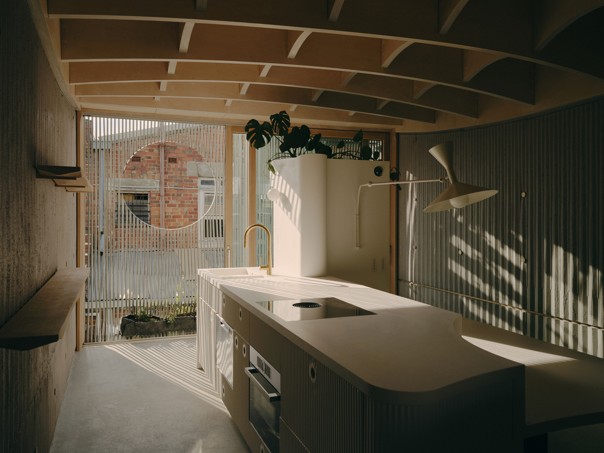 Kitchen with white stone island and vertical slat screen filtering afternoon sunlight from the courtyard