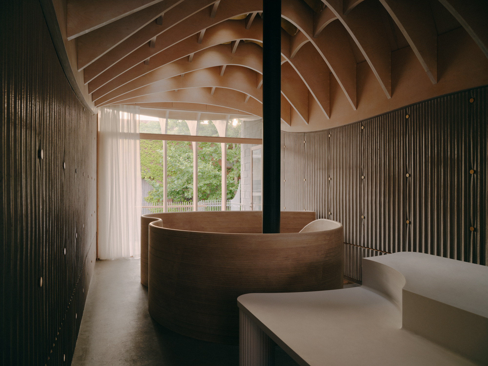 Interior reception area with curving timber desk beneath a ribbed timber ceiling and vertical slat walls