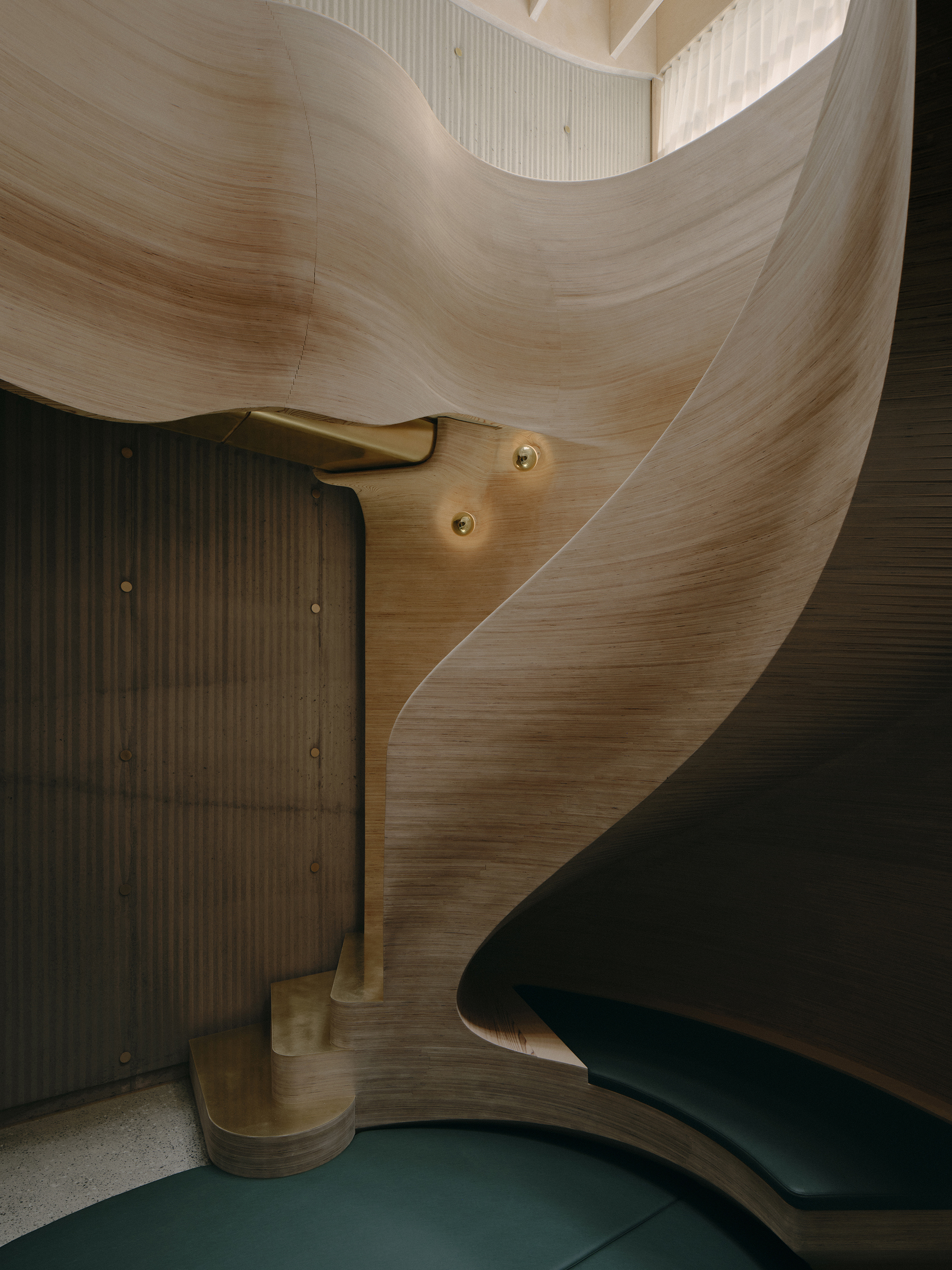 Detail of brass handrail anchoring into laminated timber wall next to vertical slat partition