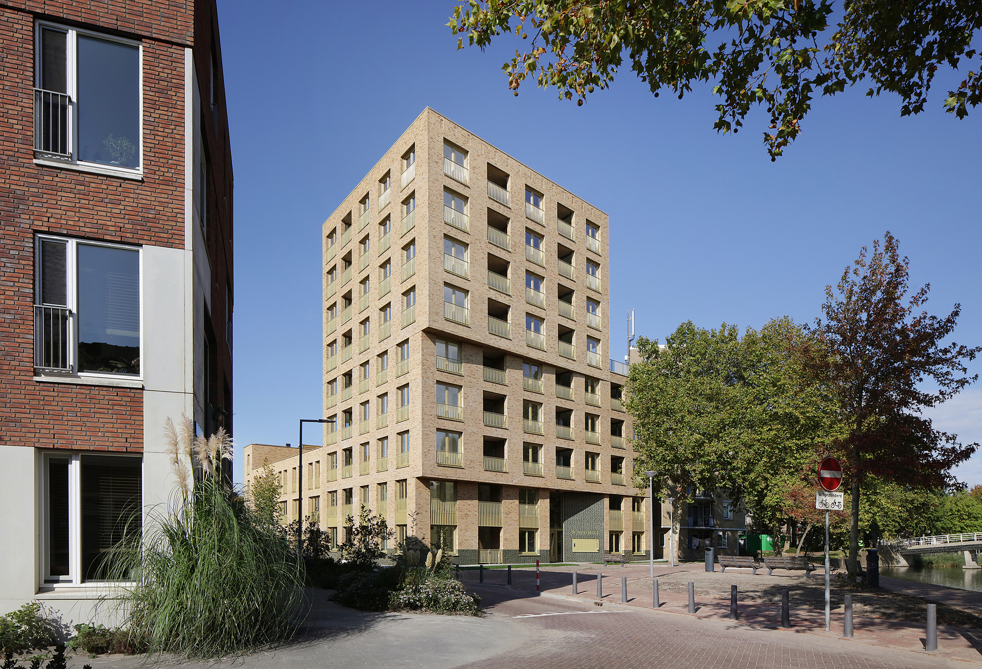 Street view of the gridded brick tower with a cantilevered mid-section under a clear blue sky