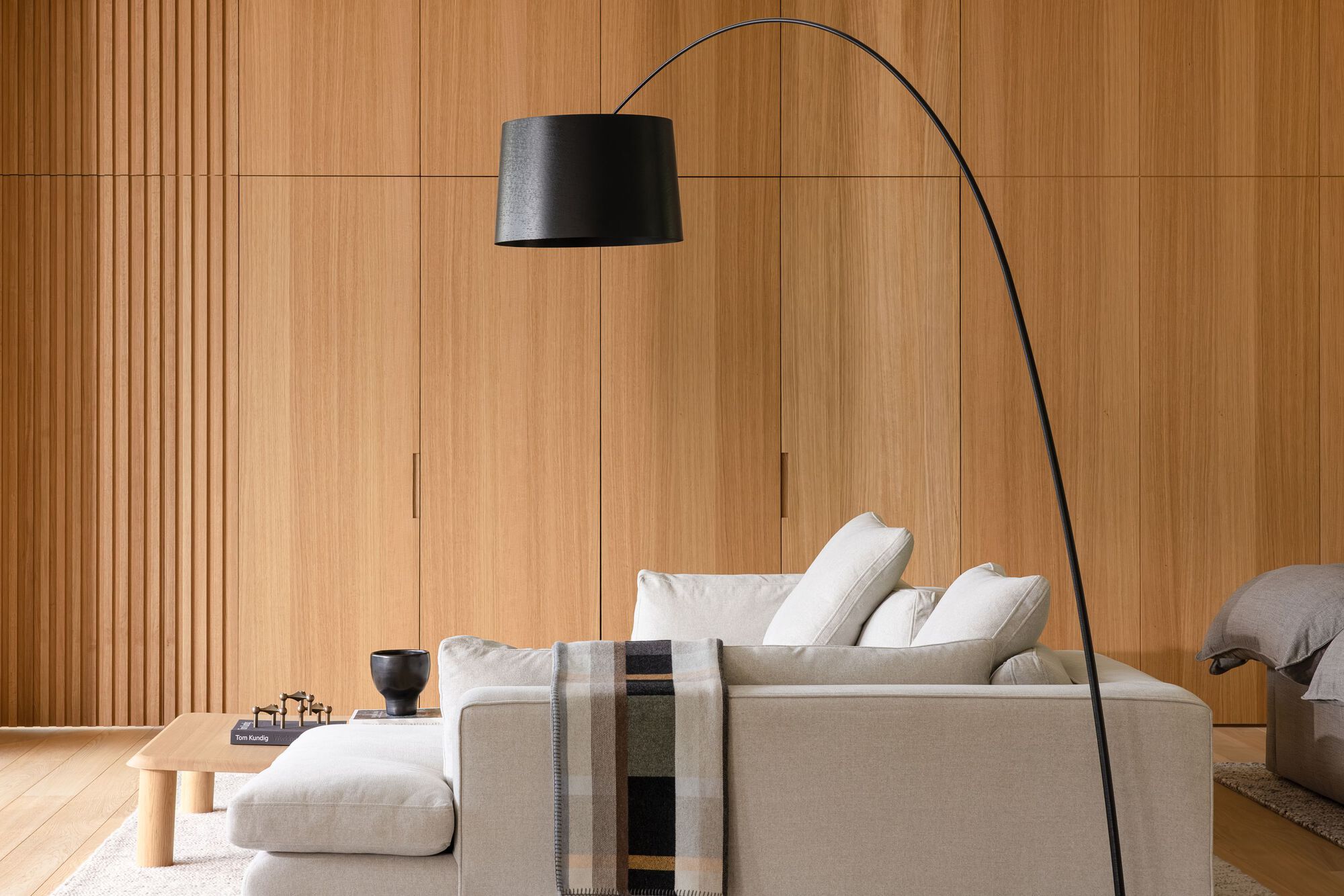 Living room with floor-to-ceiling timber paneling and an arcing floor lamp over seating