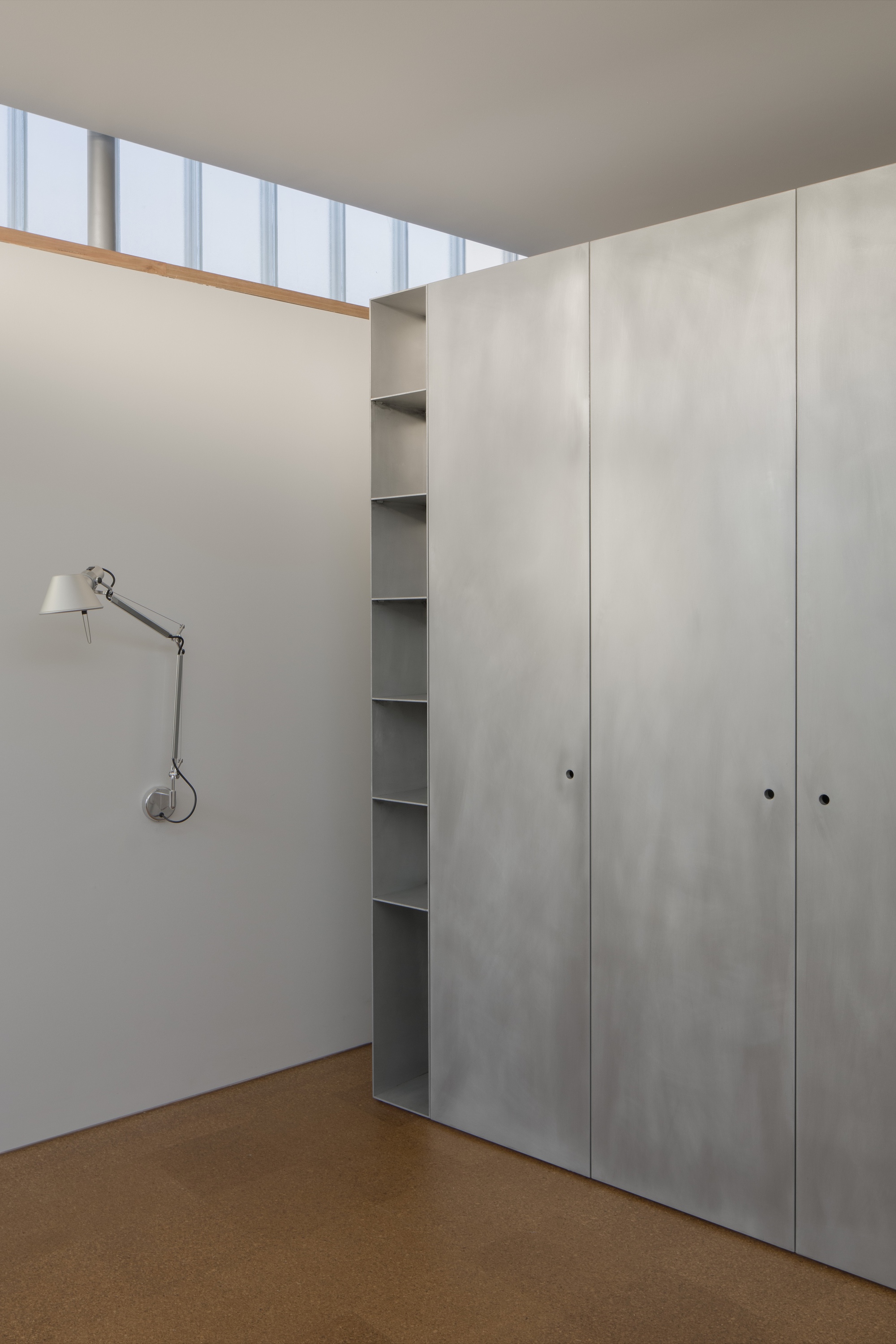 Corner of bedroom showing light grey joinery panels and continuous clerestory glazing above