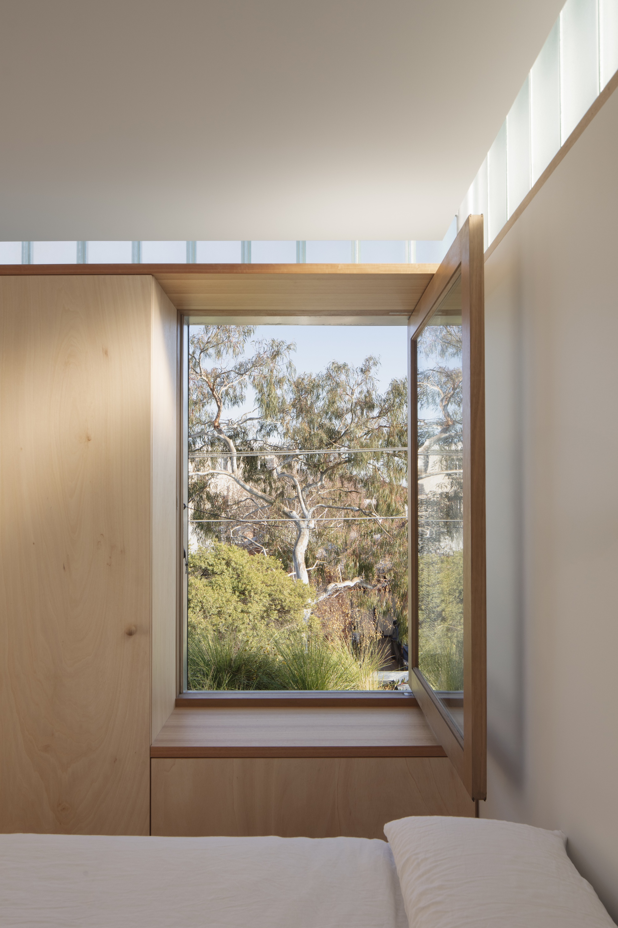 Timber window seat framing a view of eucalyptus trees and native grasses outside