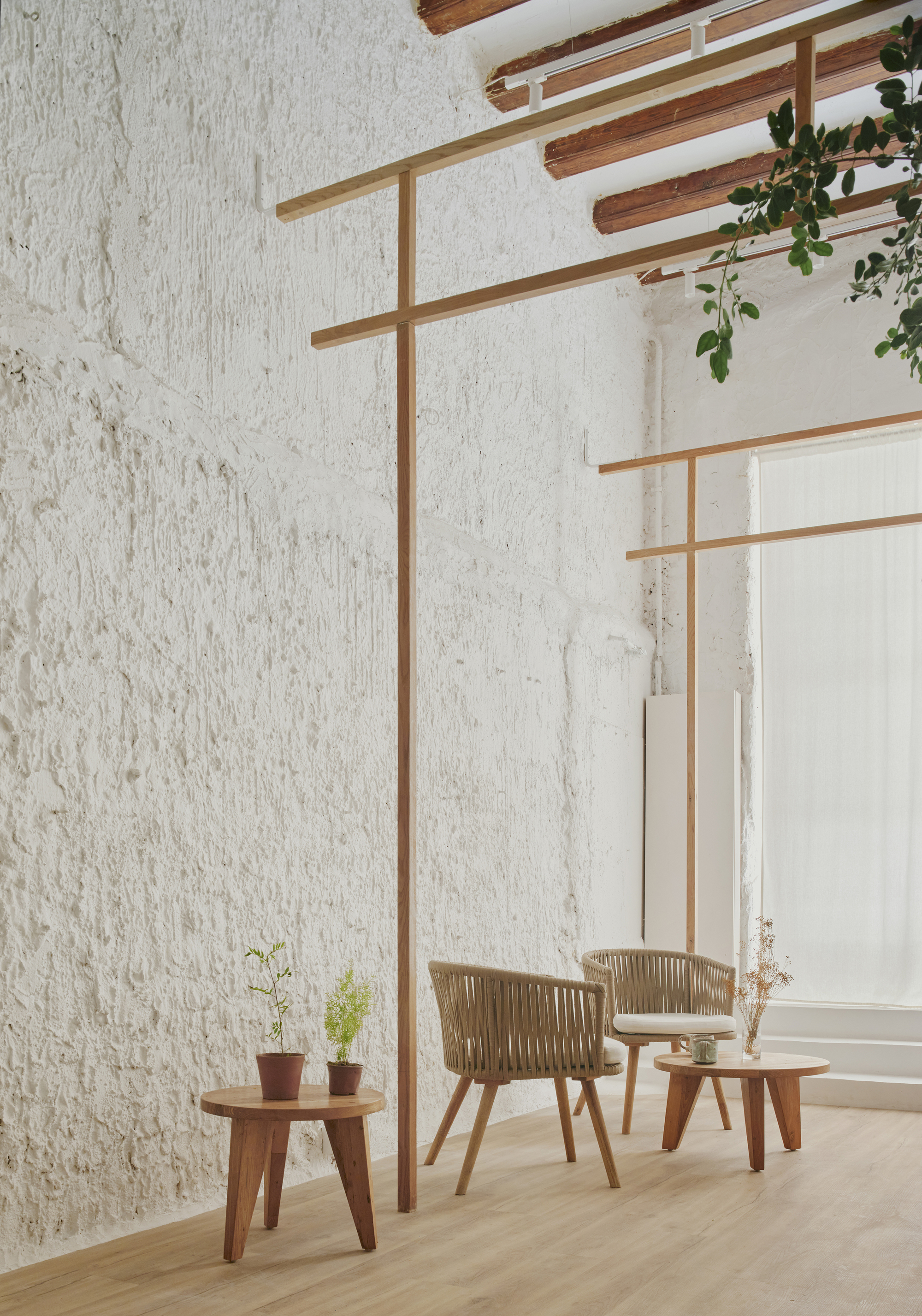 Interior seating area with whitewashed stone walls, exposed timber beams, and timber frame partitions with potted plants