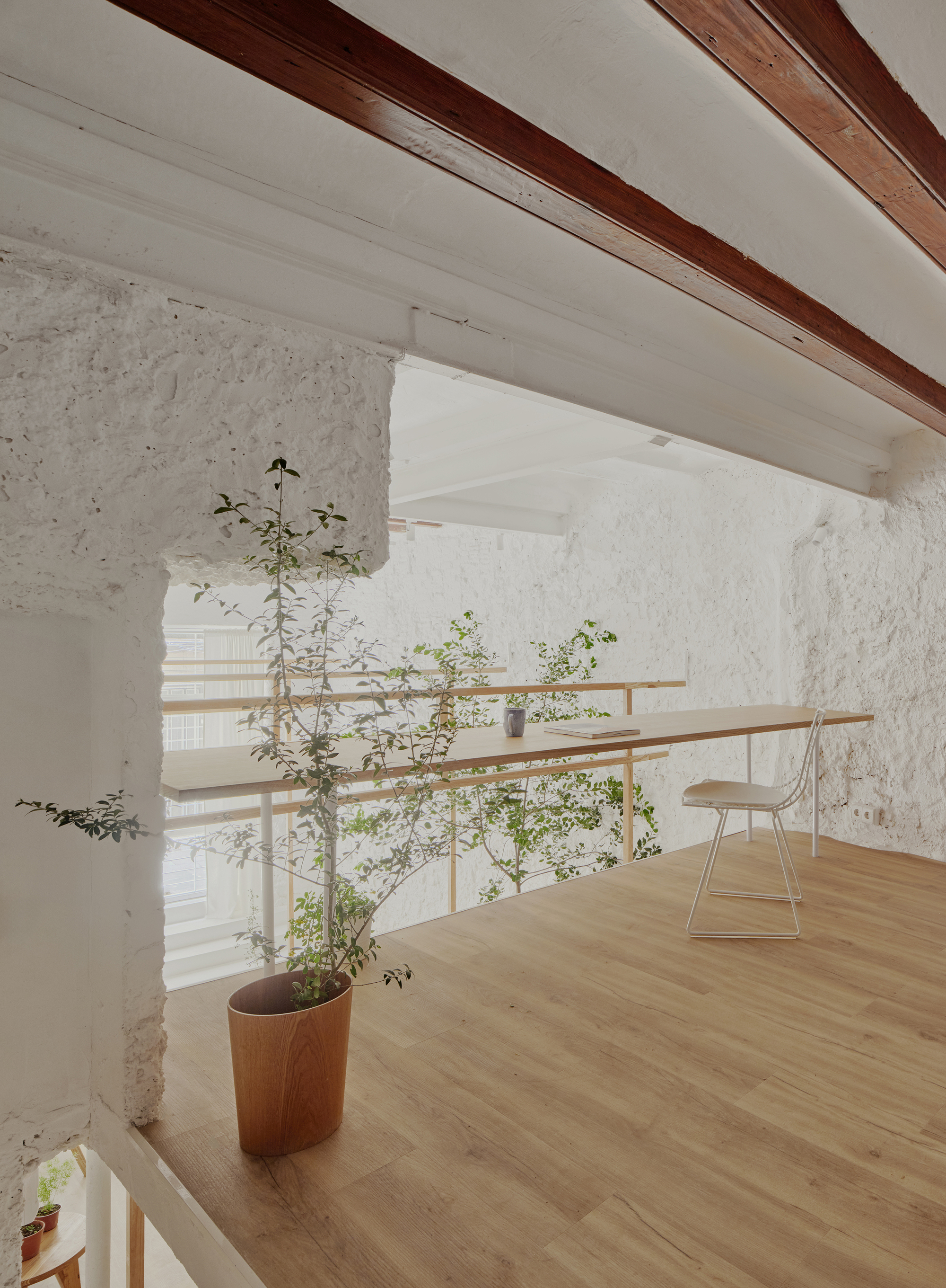 Upper level view with exposed timber ceiling beams and horizontal timber railings overlooking the double-height space