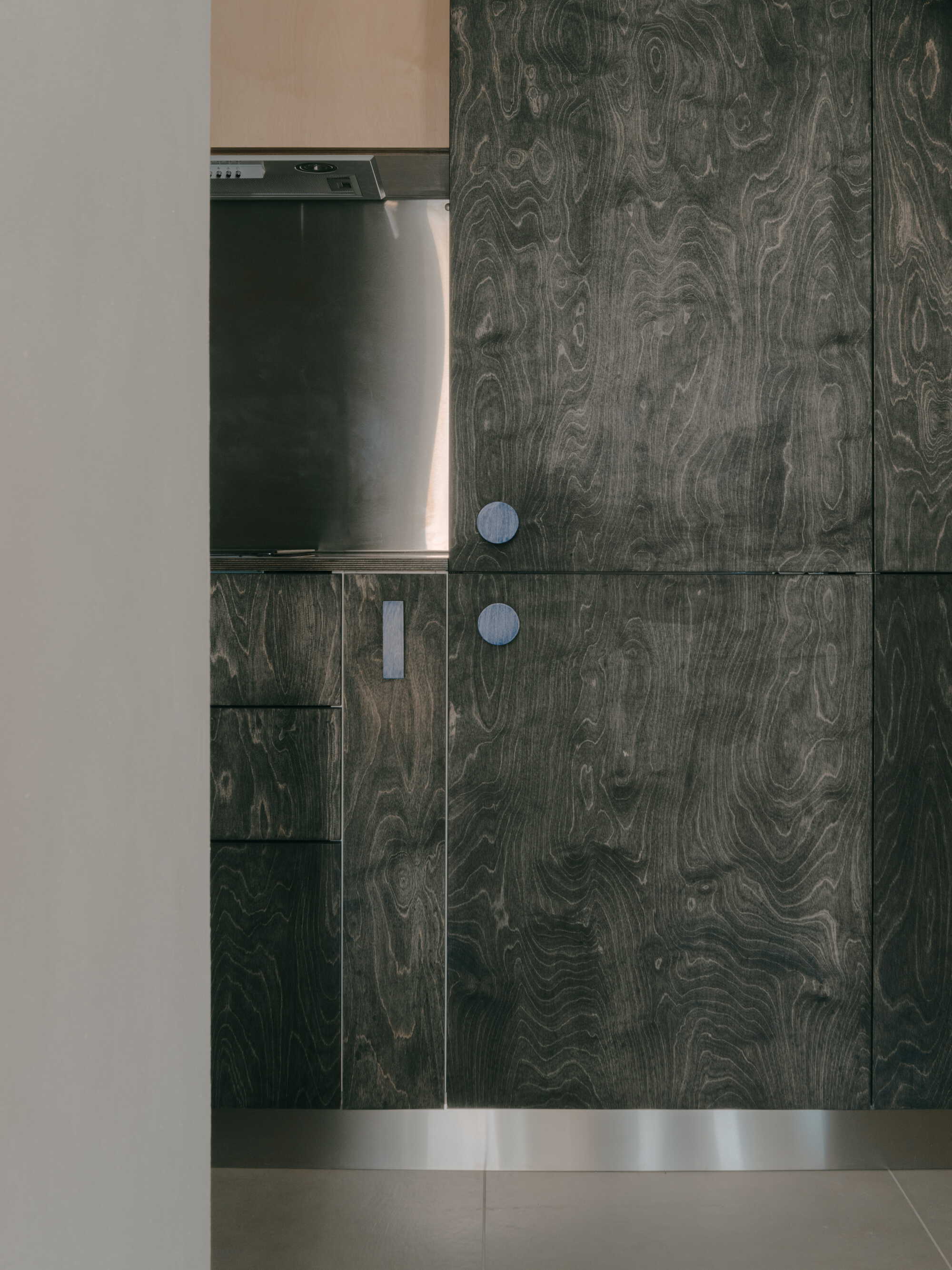 Dark wood grain kitchen cabinetry with circular pulls beside a stainless steel appliance