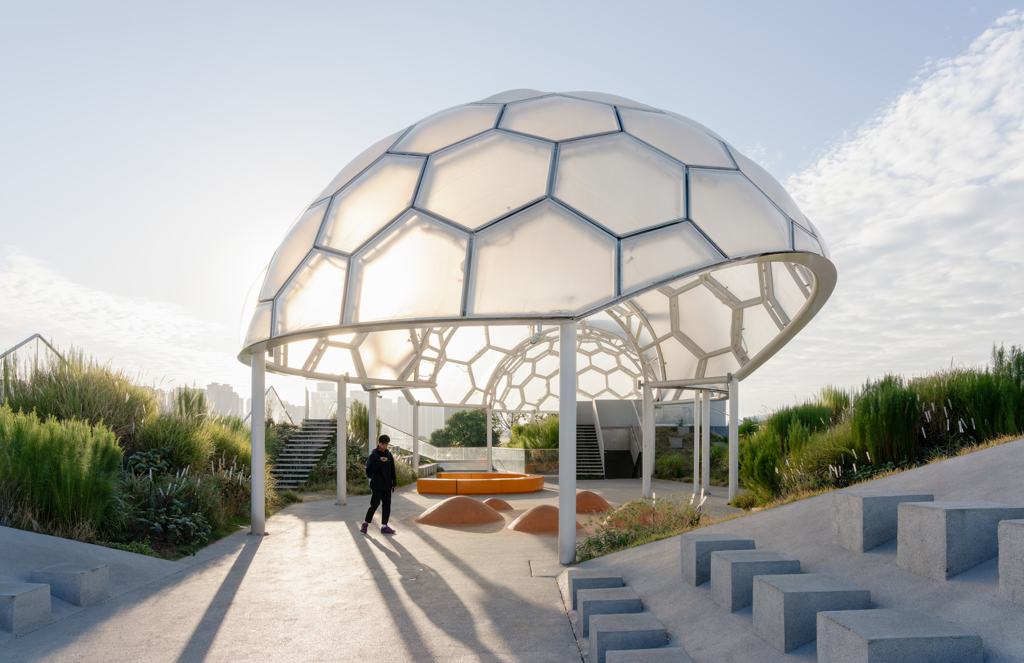 Hexagonal dome pavilion with translucent panels and structural frame casting long shadows at sunset