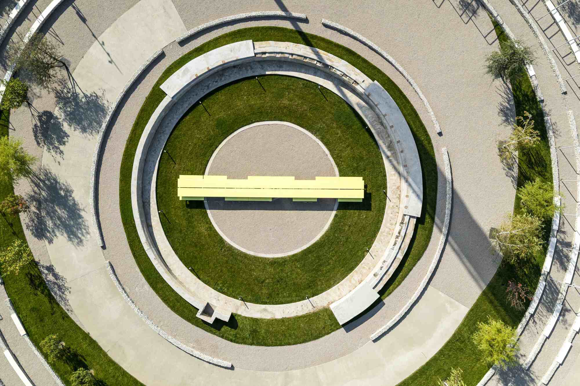 Overhead view of concentric paved circles with lawn bands and yellow canopy at center