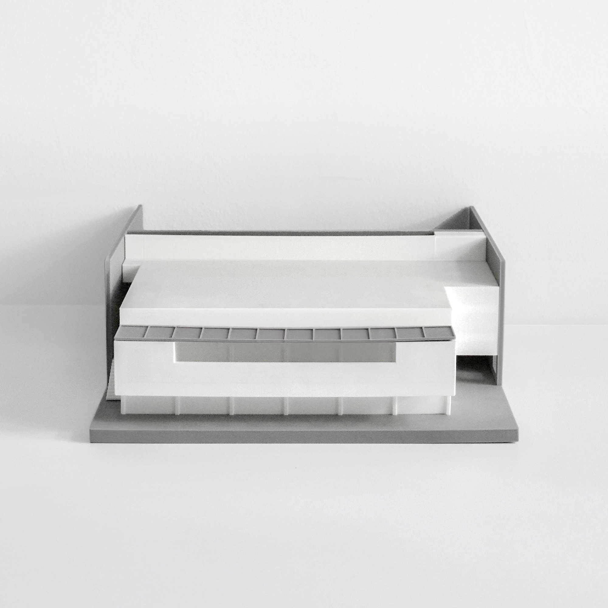 Physical scale model showing a flat-roofed volume with ribbon glazing and a cantilevered upper floor