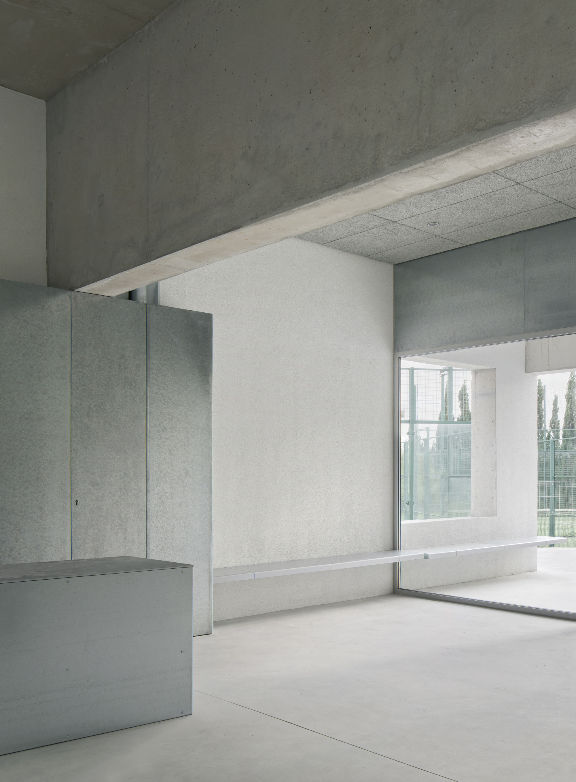 Interior room with concrete ceiling and window framing trees beyond the exterior wall