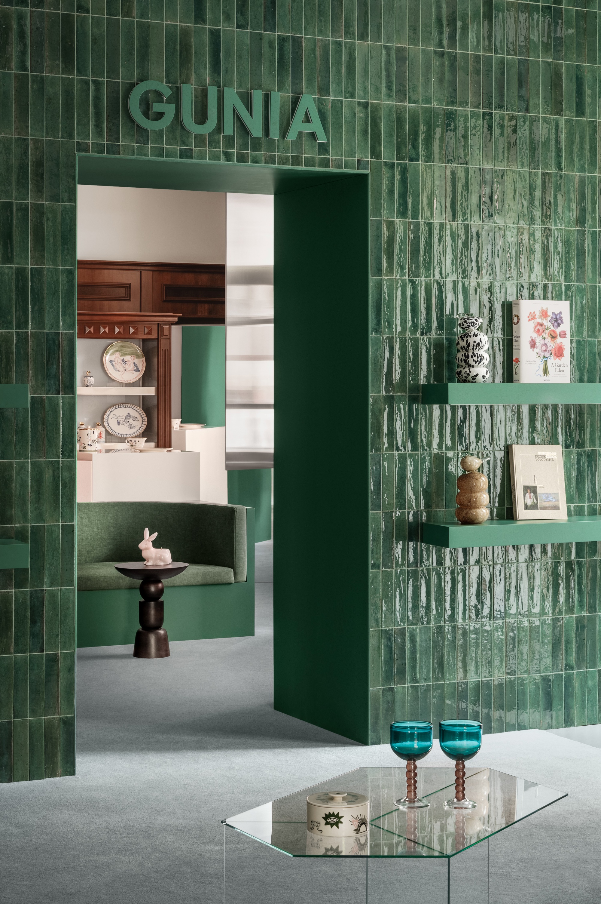 Glazed green ceramic tile wall with integrated shelving and doorway framing view to adjacent room