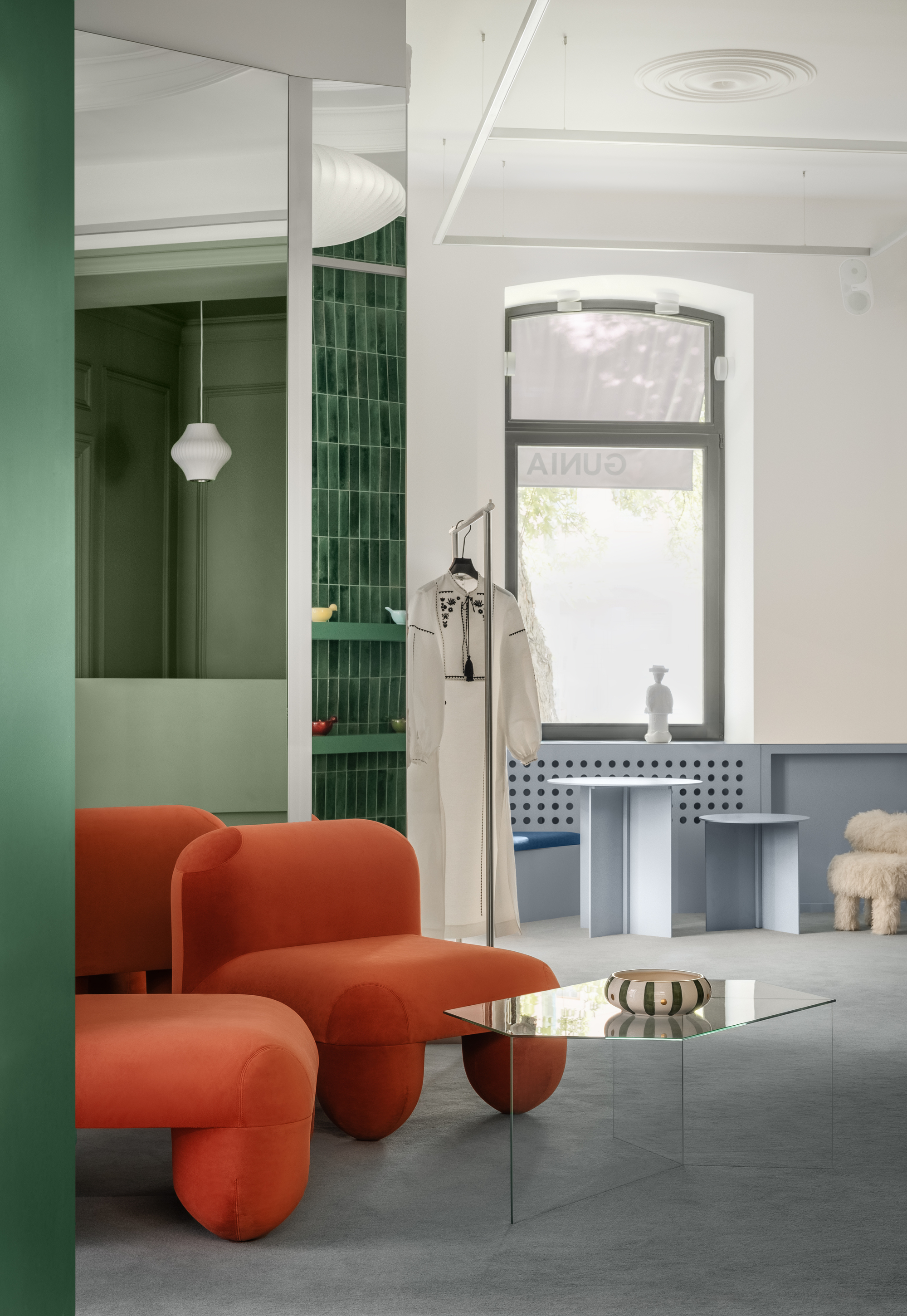 Interior with arched window, green tiled niche, and pendant light casting shadows on polished concrete floor