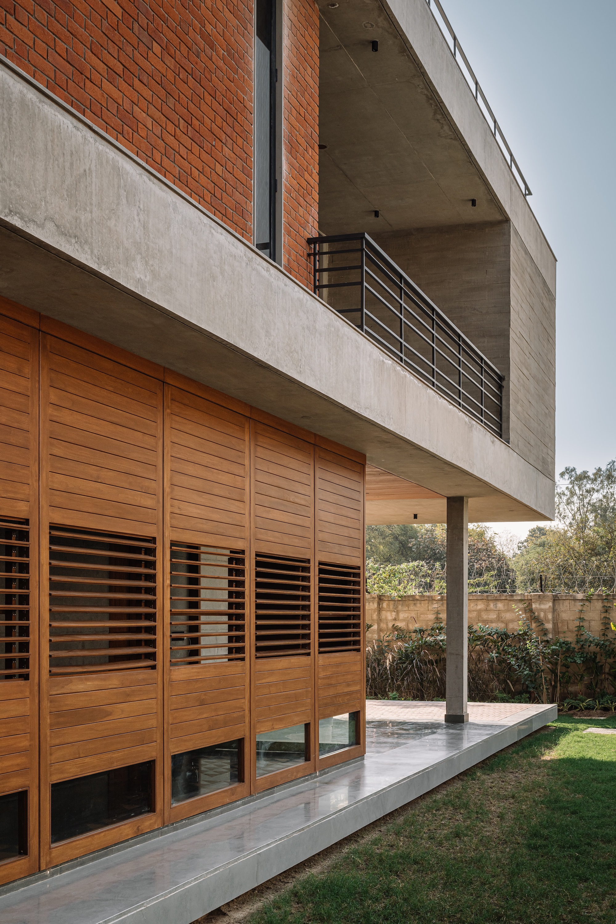 Facade detail showing horizontal timber louvered screens below cantilevered concrete balcony with metal railing