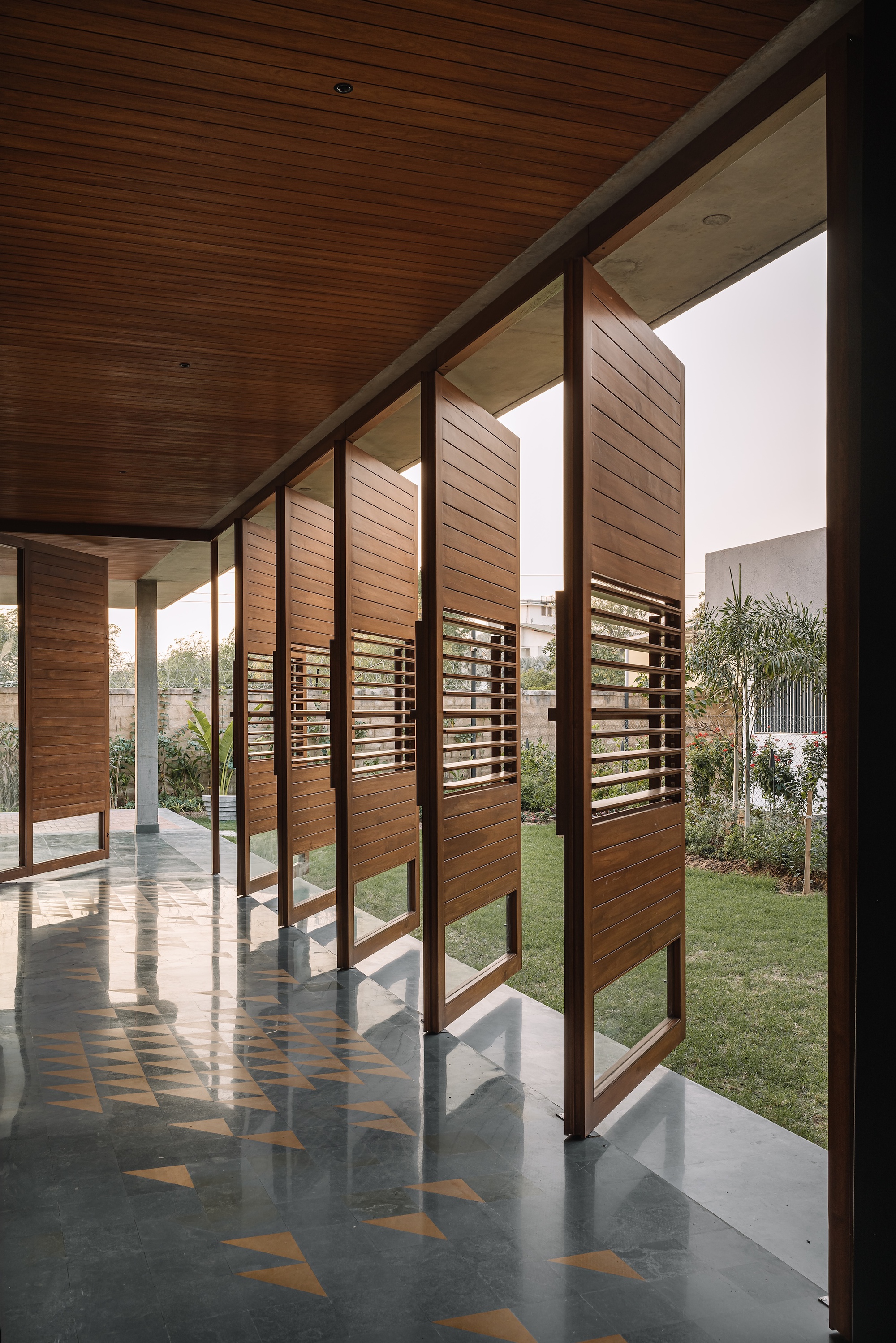 Timber screen panels filtering daylight along a corridor with exposed wood ceiling and patterned floor