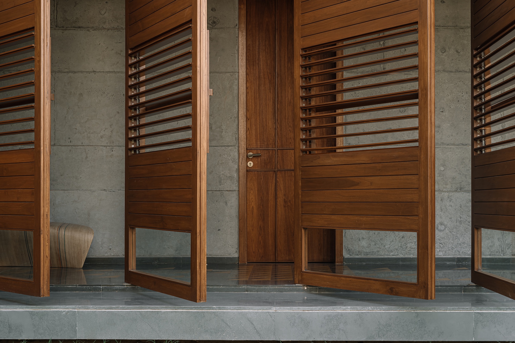 Entry threshold showing timber louvered doors between concrete columns and polished concrete floor