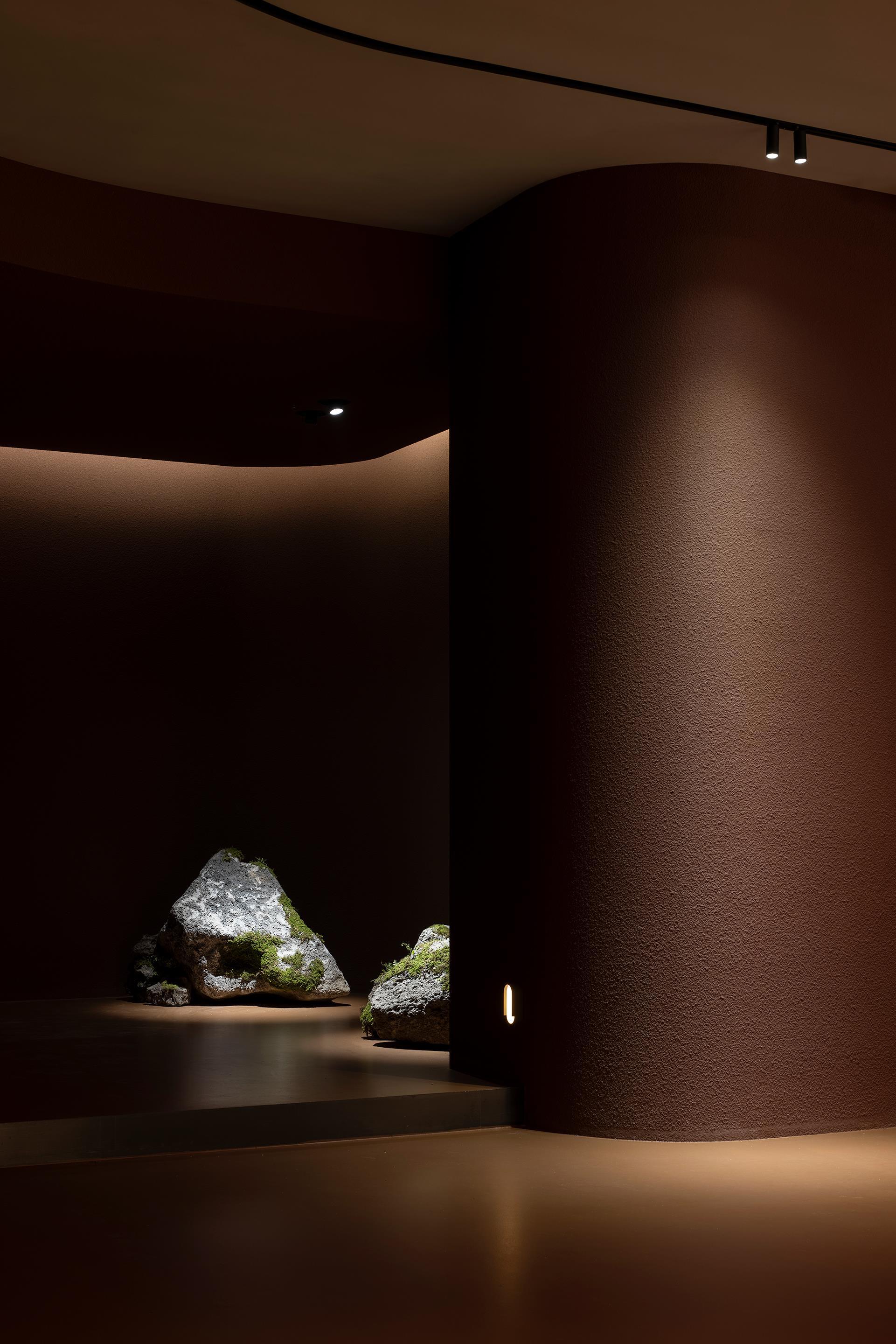 Curved alcove with moss-covered stones on platform beneath concealed perimeter lighting