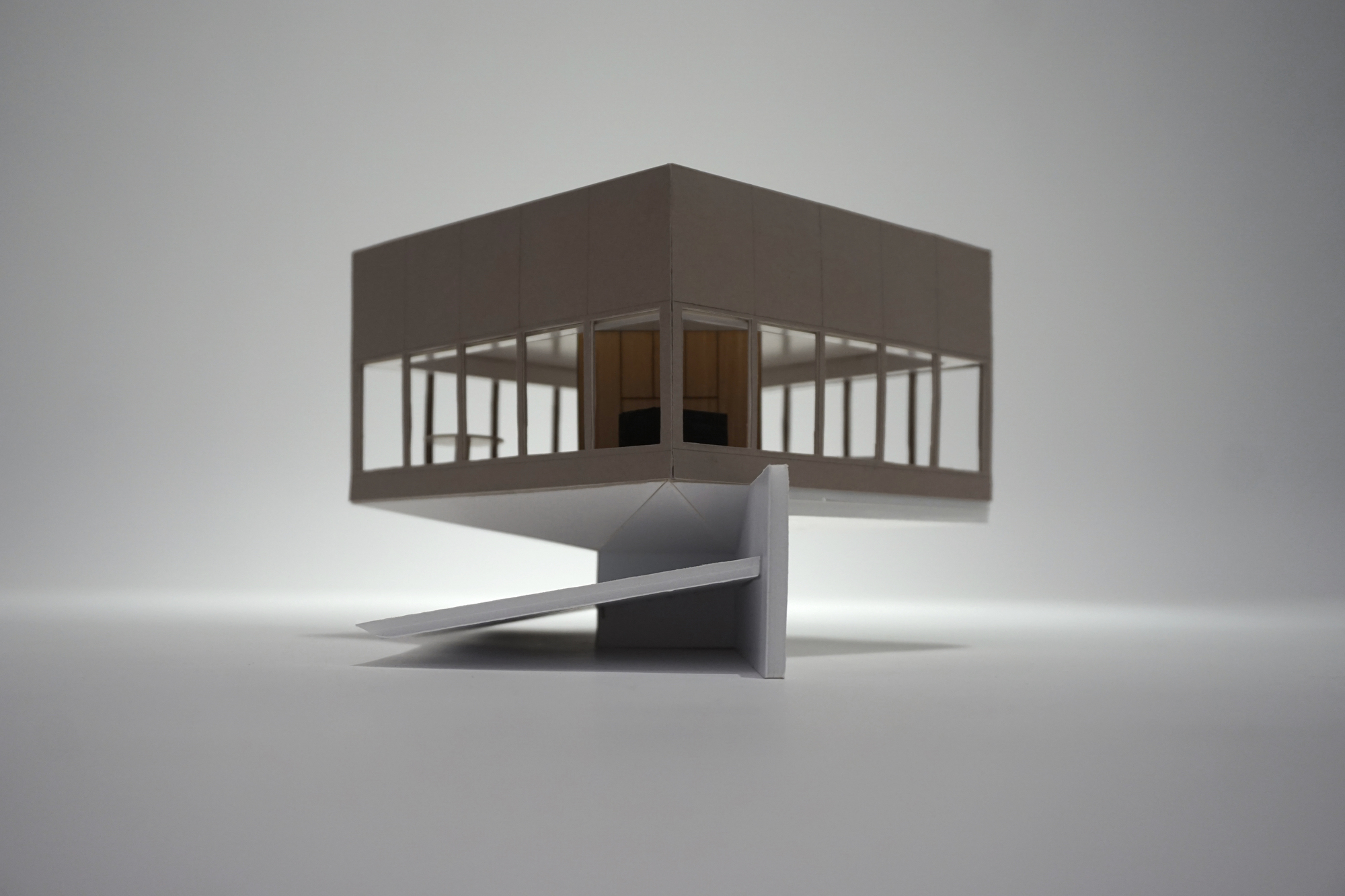Physical model of an elevated pavilion on a concrete pedestal with a folded access ramp