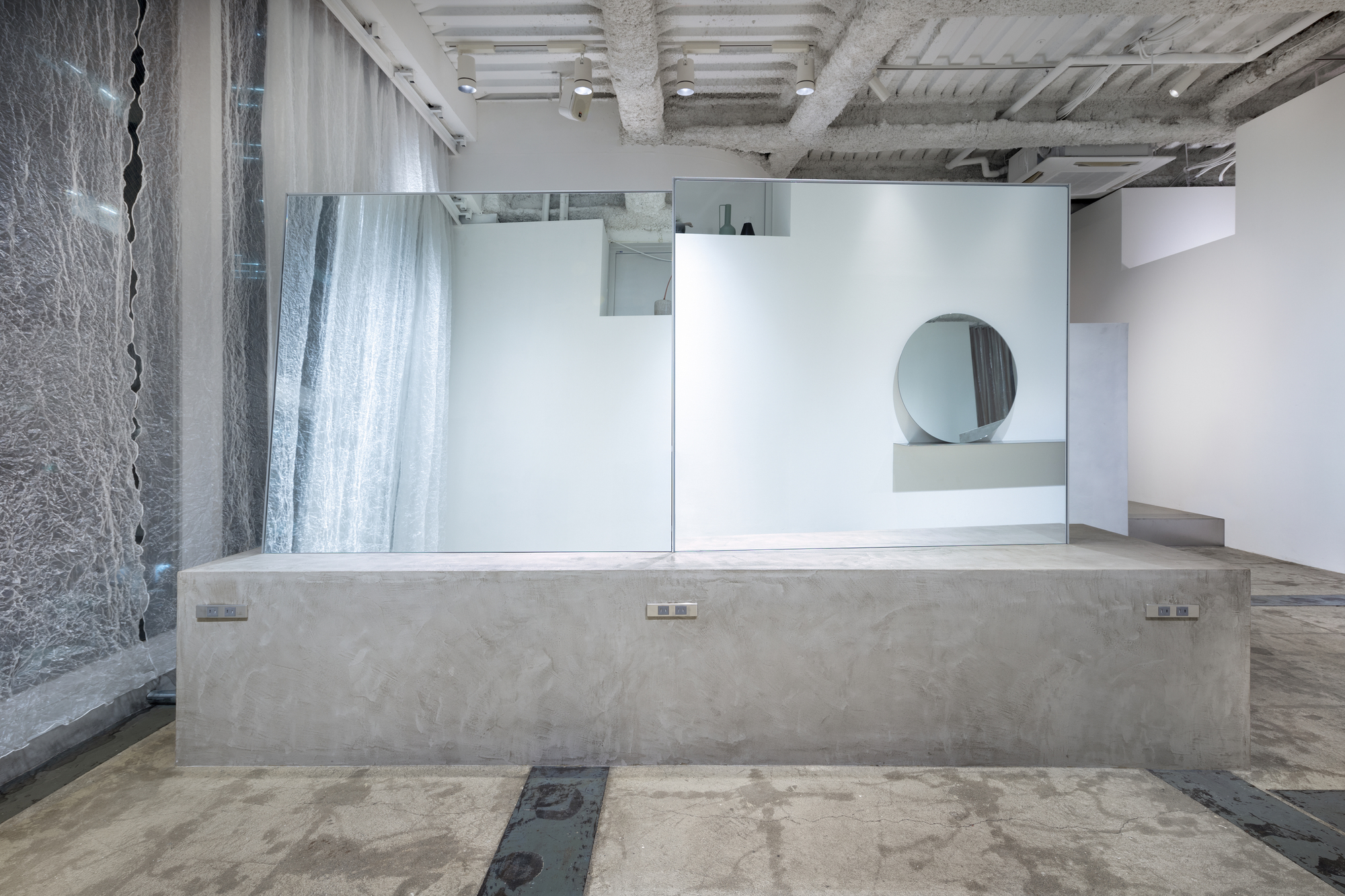 Long concrete counter with embedded outlets facing white partitions and exposed structural beams overhead