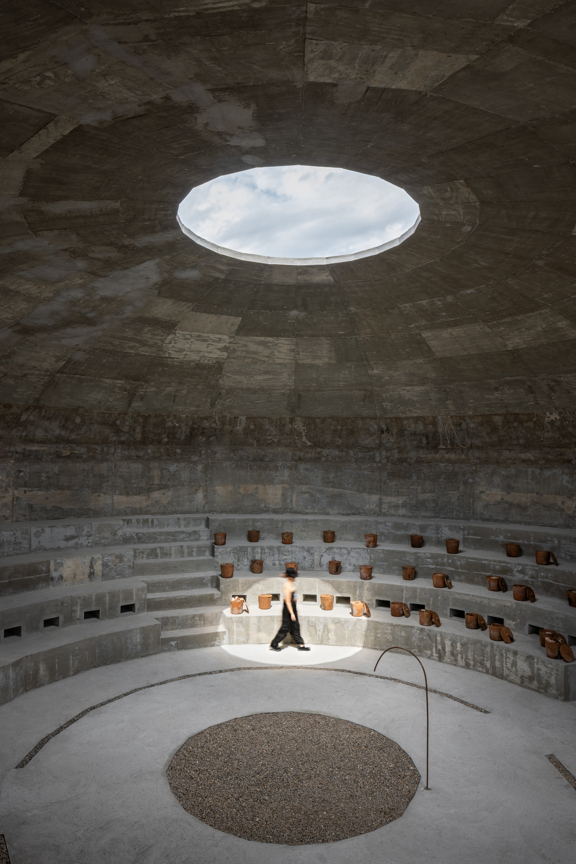 View up to the circular oculus in the dome ceiling with a figure seated on the lower benches