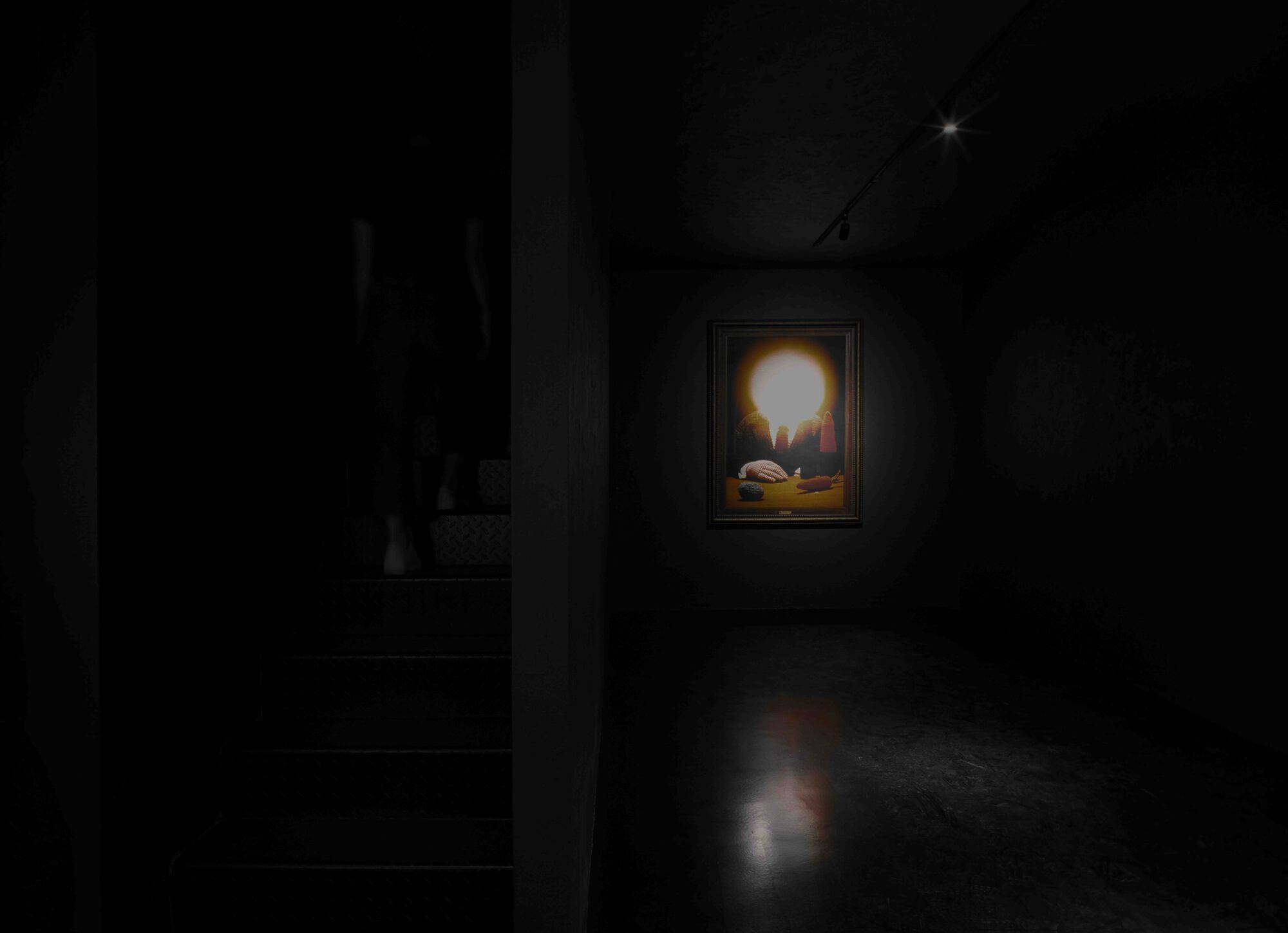 Illuminated painting on a dark gallery wall casting a soft glow onto polished concrete flooring