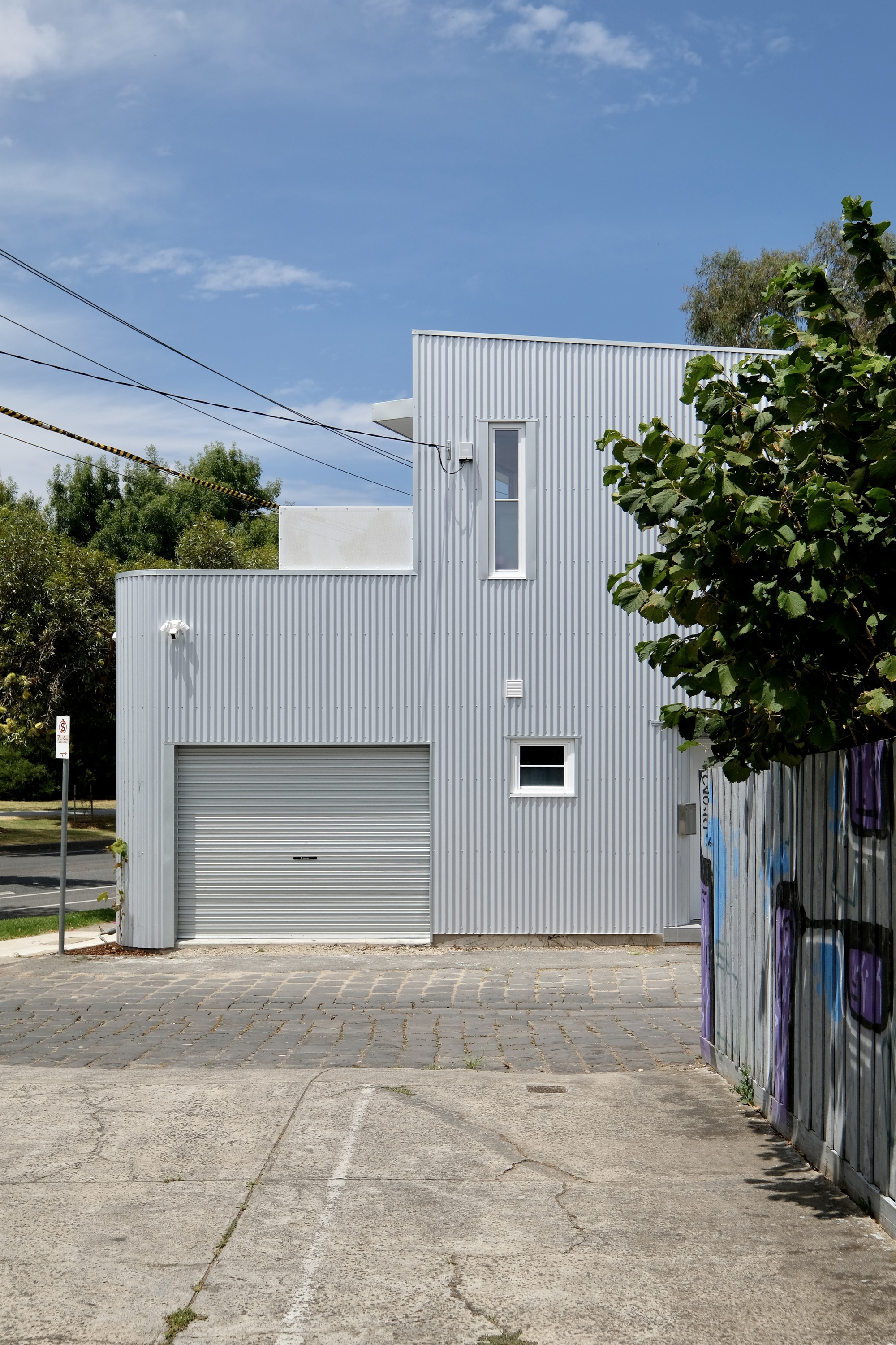 Front elevation showing the roll-up garage door and vertical window in corrugated cladding