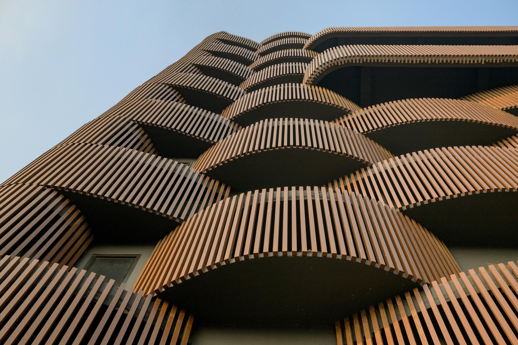 Upward view of the staggered terracotta-clad balconies wrapping the tower volume