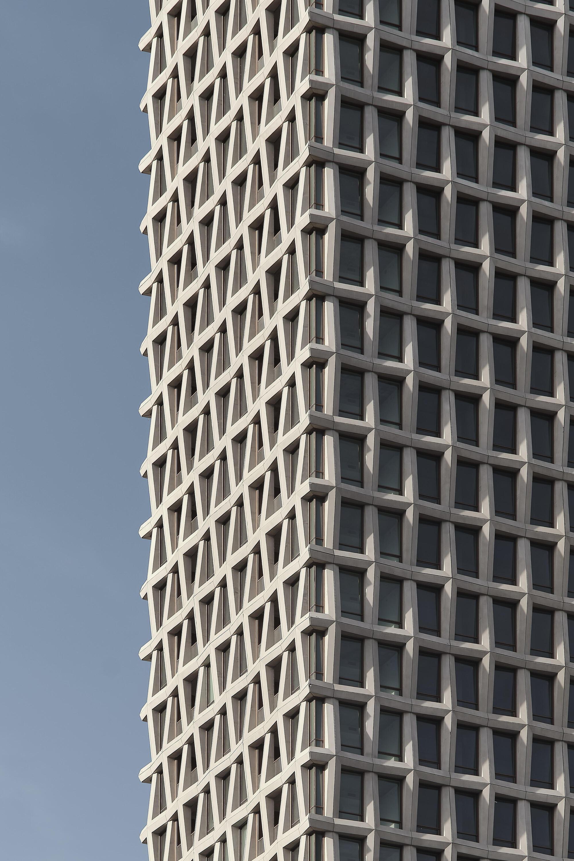 Close-up of the diagonal grid window pattern created by angled concrete mullions