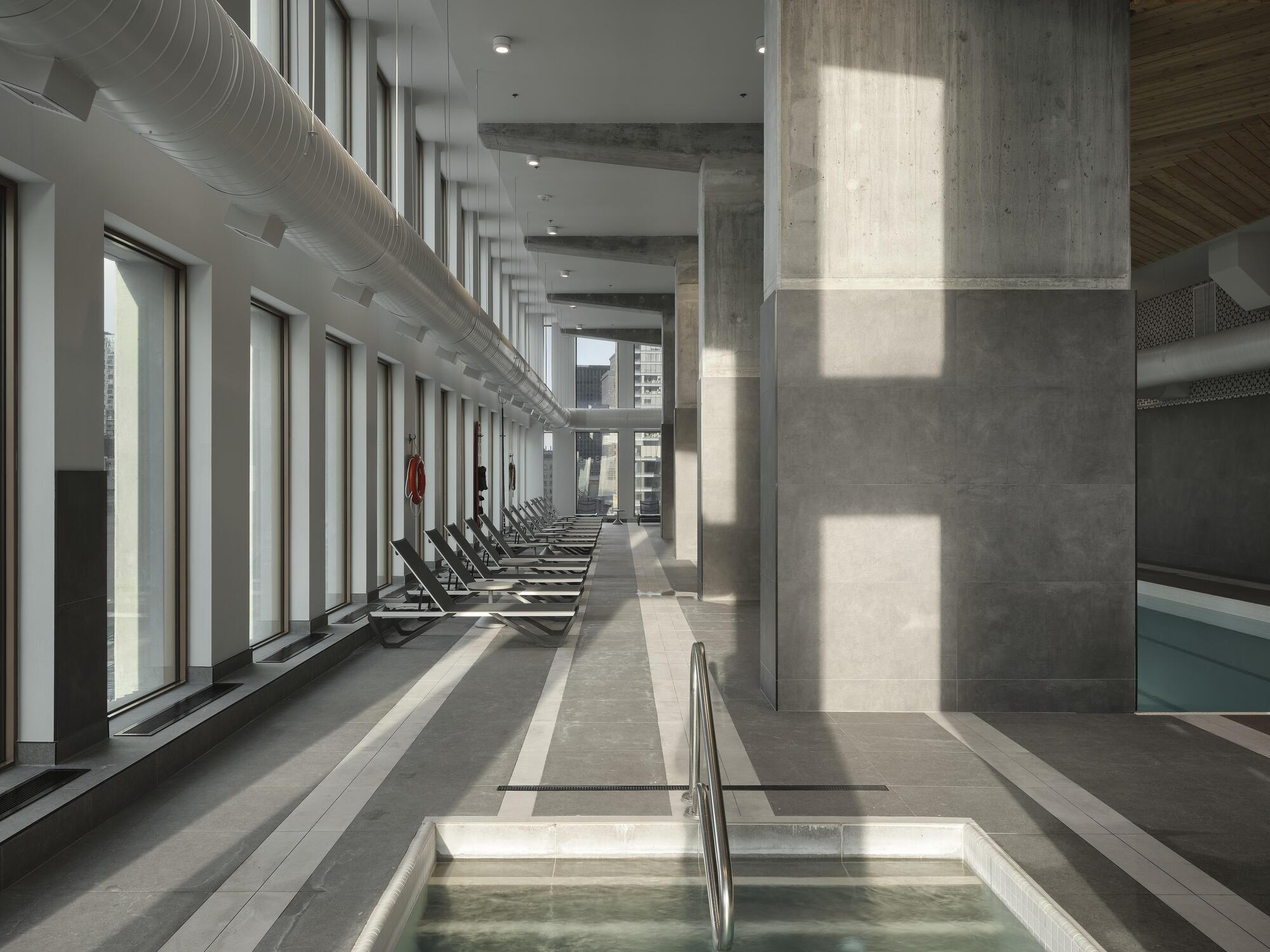 Pool deck with concrete columns casting rectangular shadows from tall windows along the perimeter