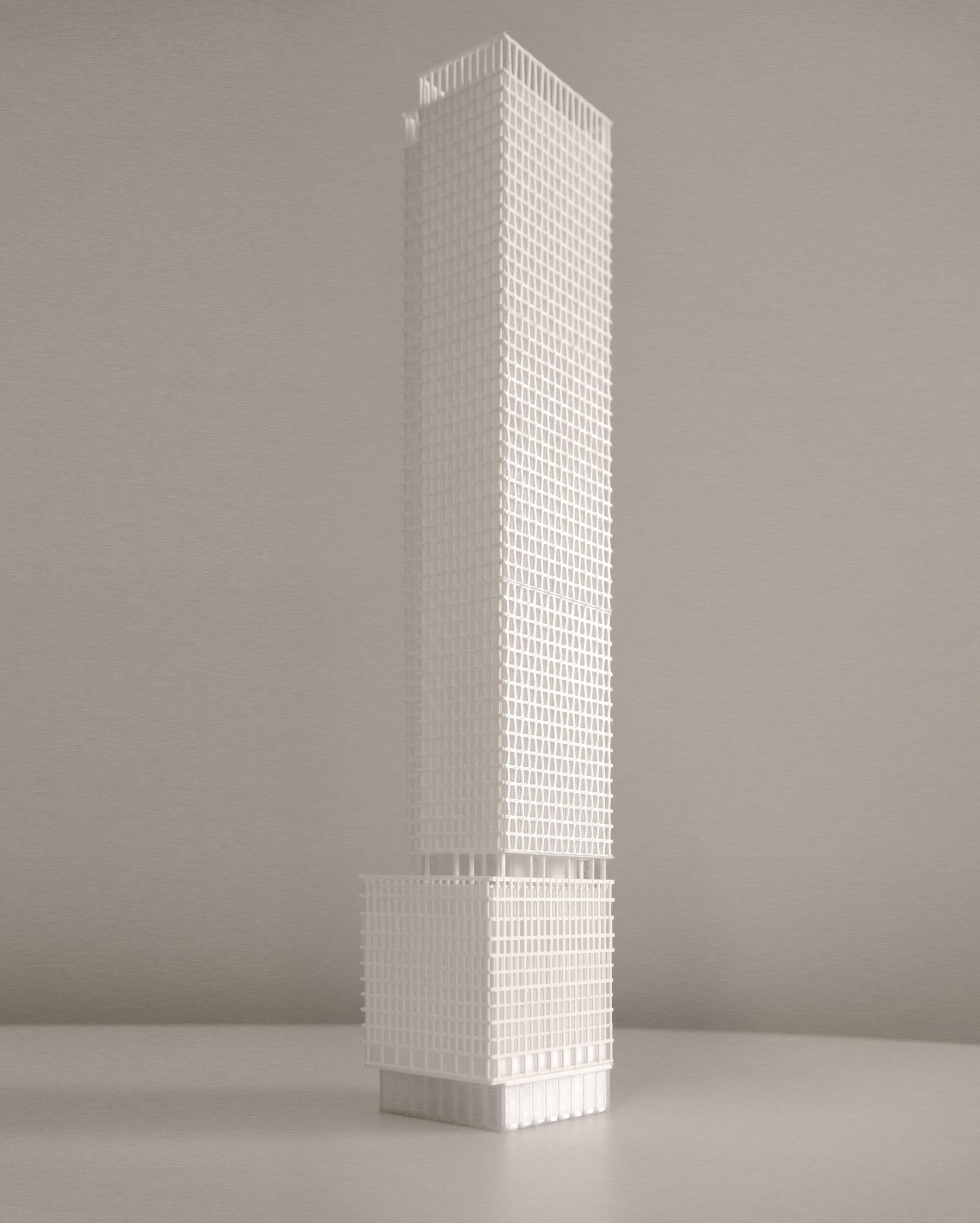 White physical model of a slender tower with gridded facade and recessed podium base