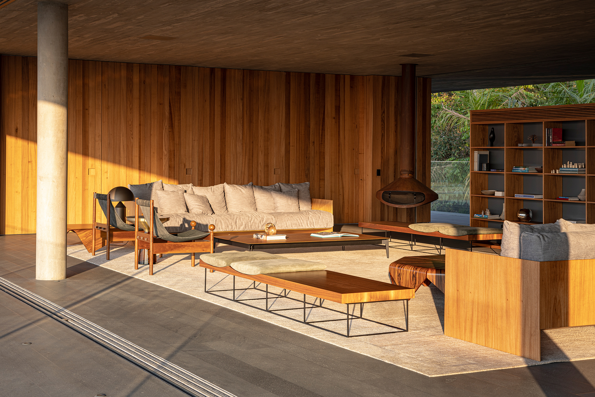 Covered lounge with freestanding fireplace and vertical timber cladding in golden afternoon sun