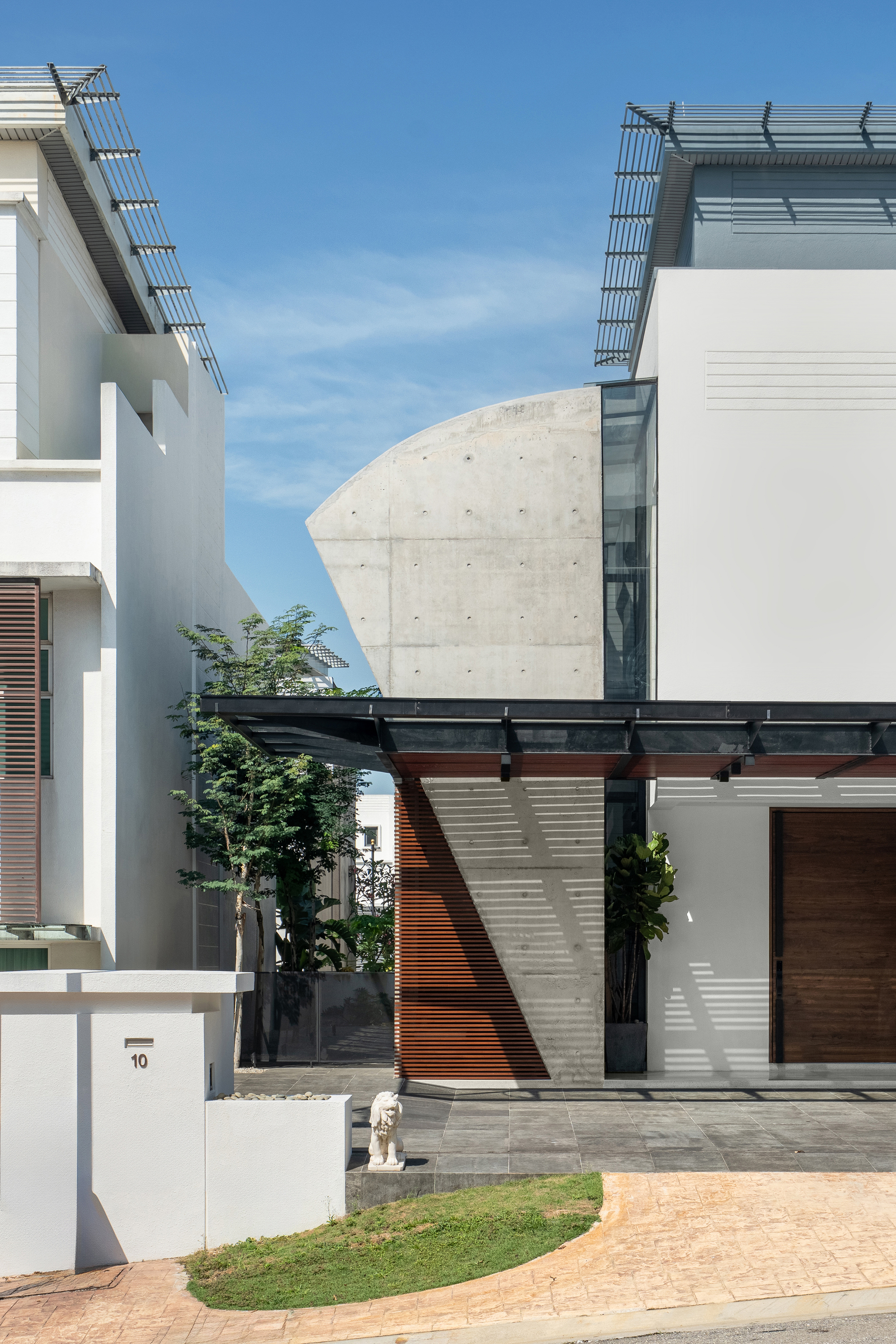 Cantilevered concrete volume with tie-hole marks above a courtyard entry framed by timber screens