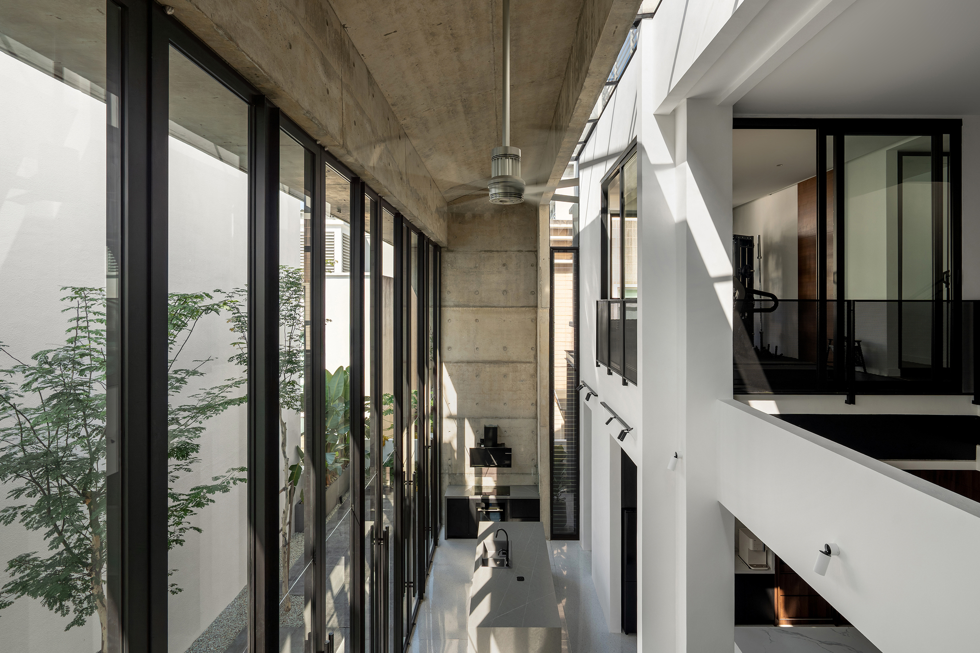 Exposed concrete ceiling beam above a multi-level circulation space with glazed courtyard walls