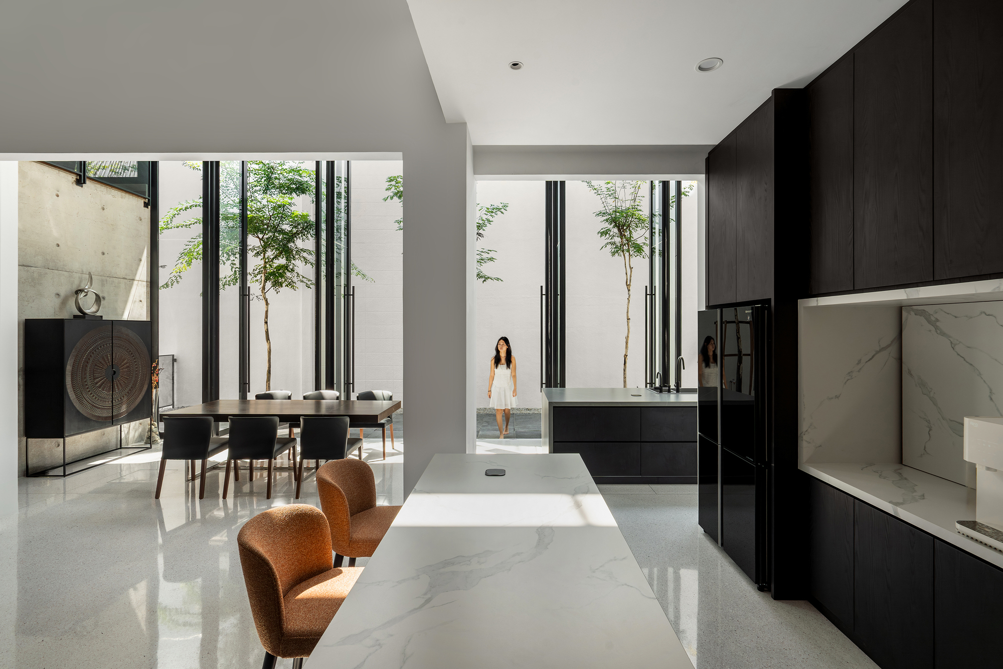 Open living and kitchen space with polished terrazzo floor and views to two planted courtyards