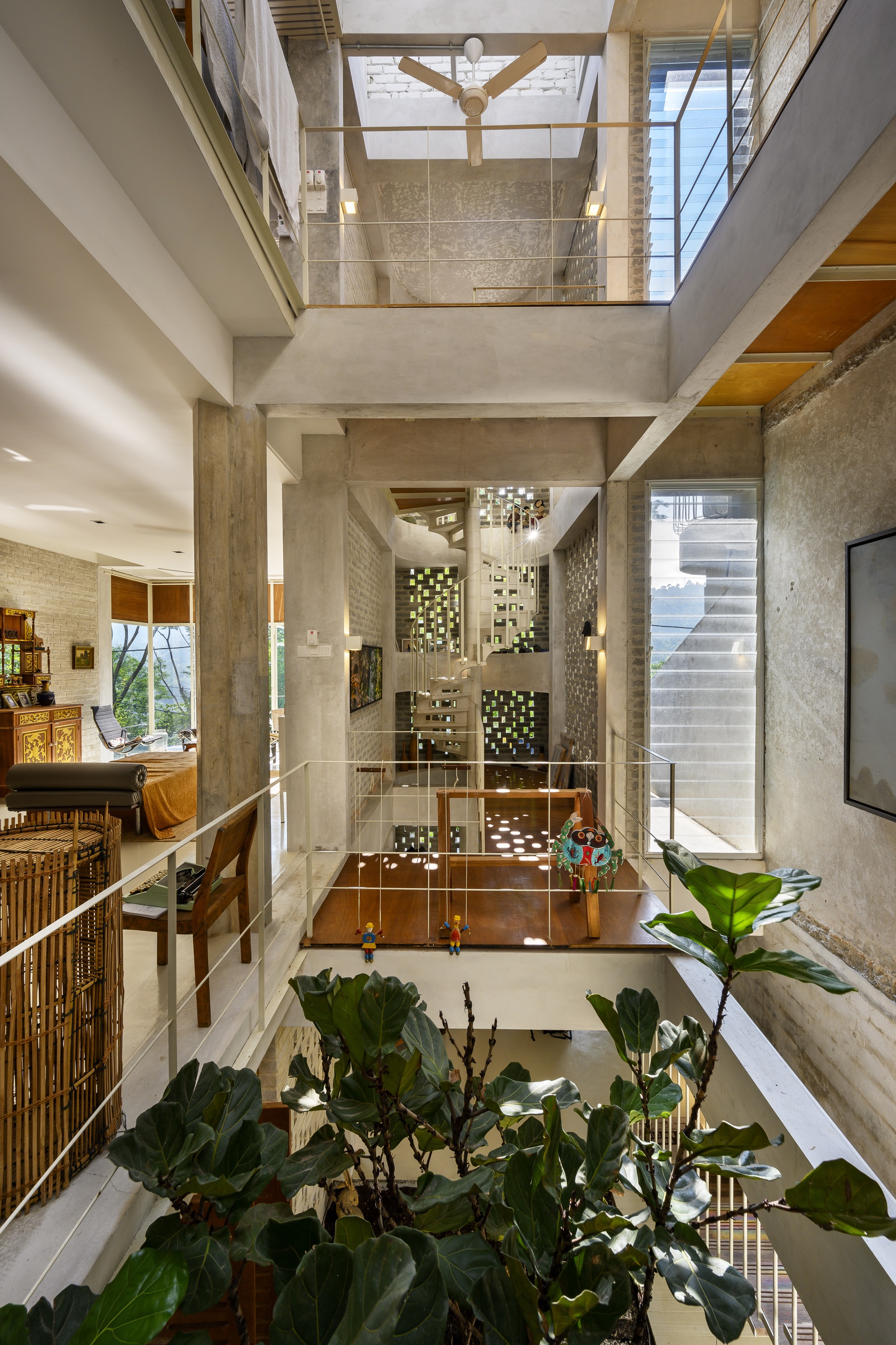 Triple-height atrium with concrete columns, exposed timber beams and planted courtyard below glass bridges