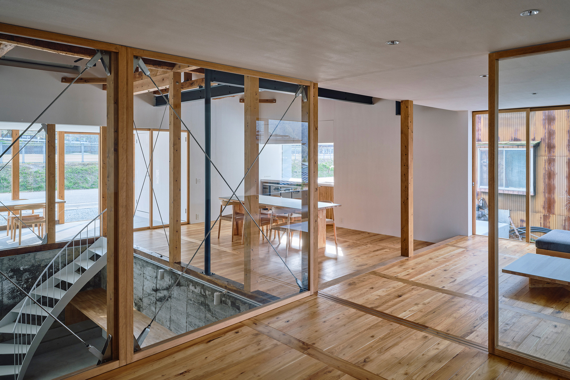 Open-plan interior with timber framing, glass partitions, and diagonal steel tension rods