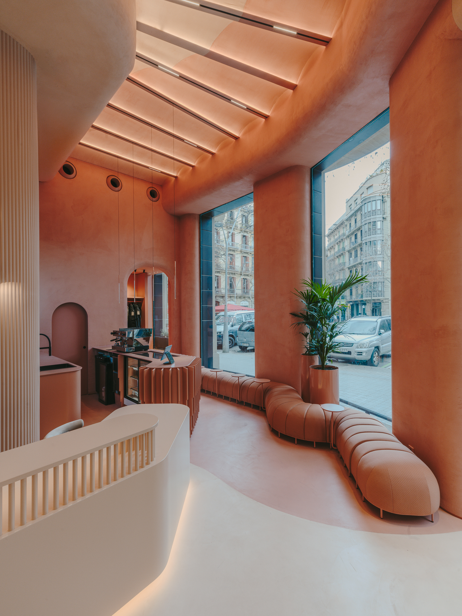 Terracotta-toned reception area with ribbed seating along tall windows overlooking the street