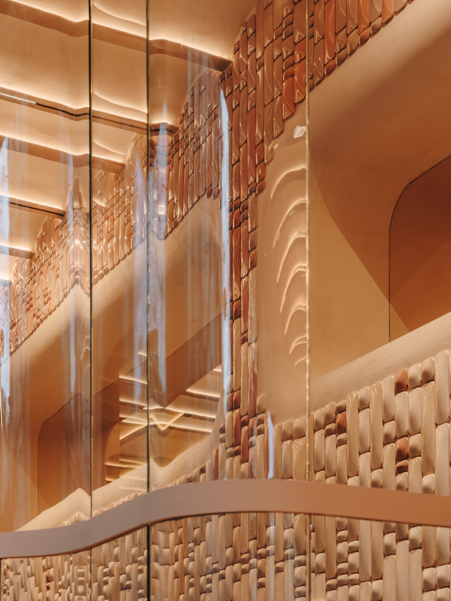 View through glass looking up at layered arched openings and woven terracotta wall surface