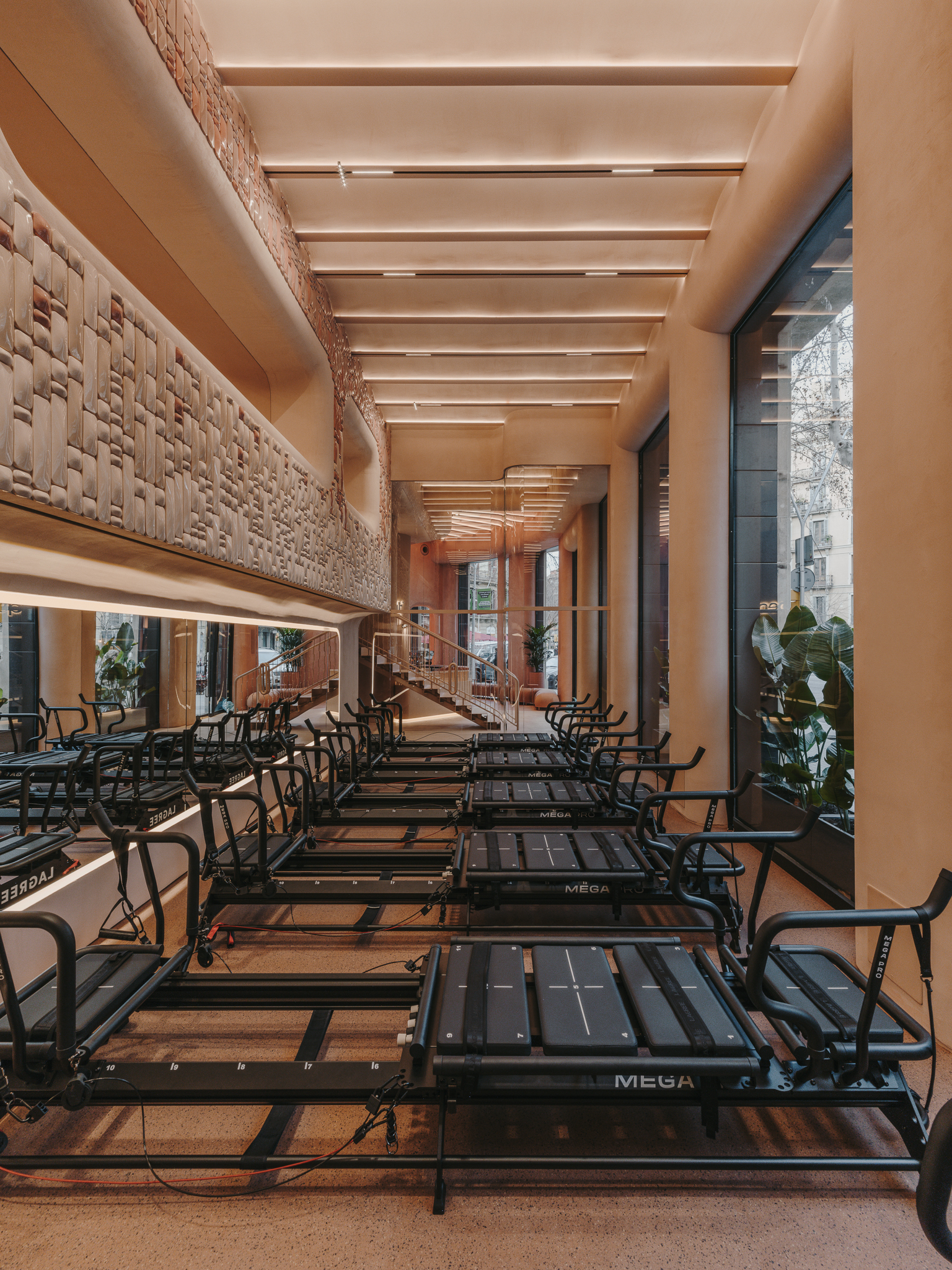 Long view down the exercise studio showing timber ceiling beams and woven wall panels flanking equipment rows