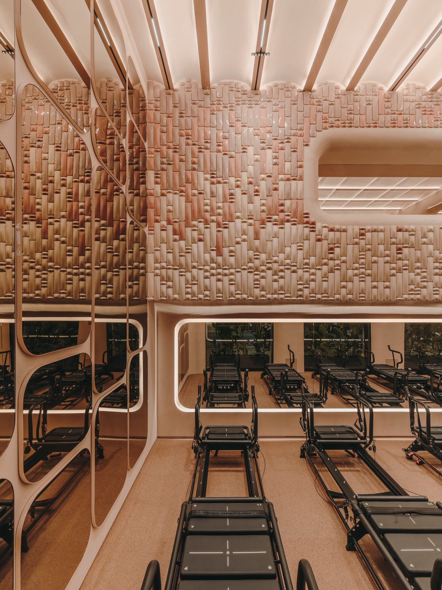 Diagonal timber bracing and basketweave wall above mirrored balcony overlooking Pilates equipment below
