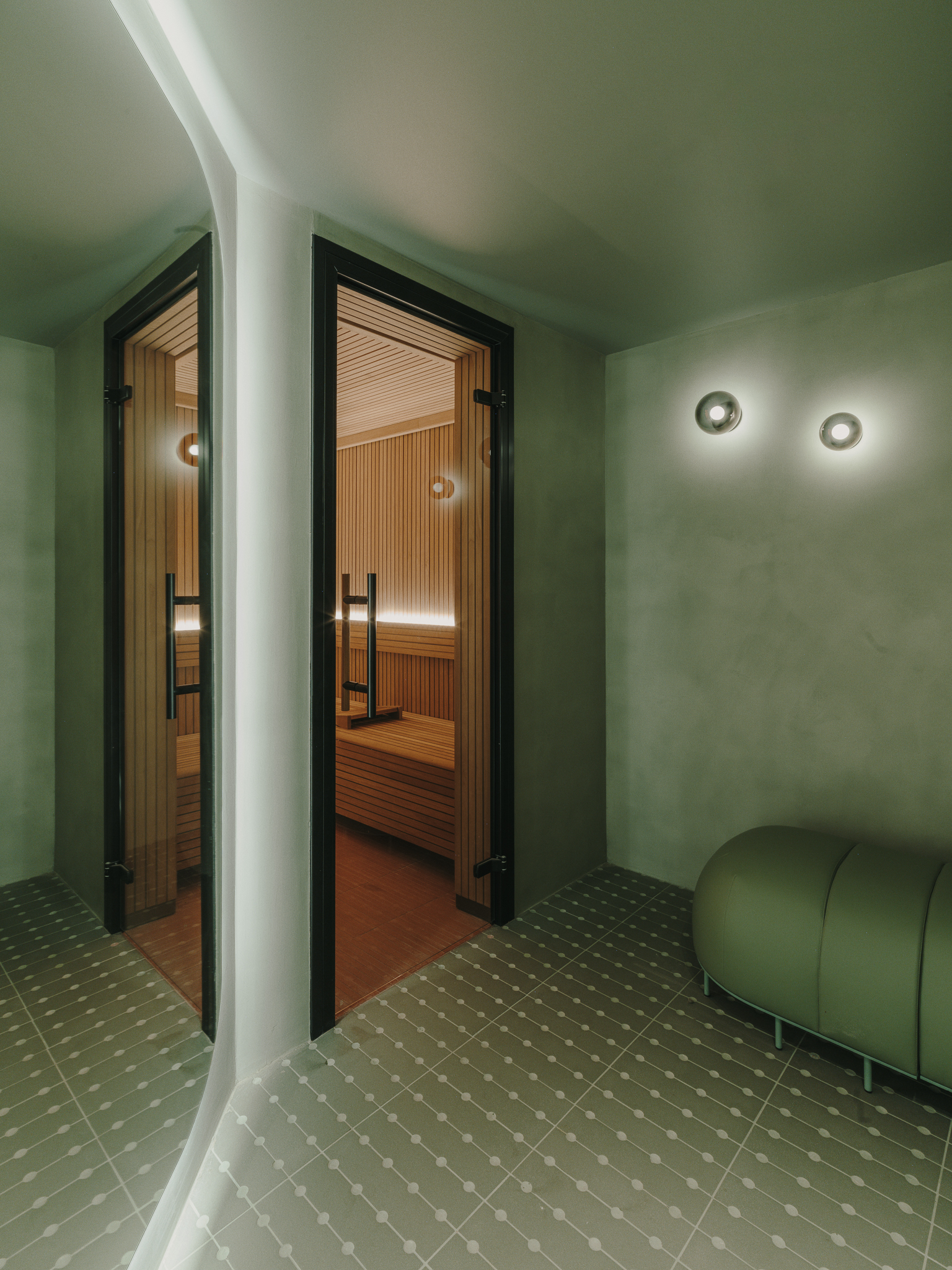 Glass-doored sauna entrance with timber interior visible beyond curved white column