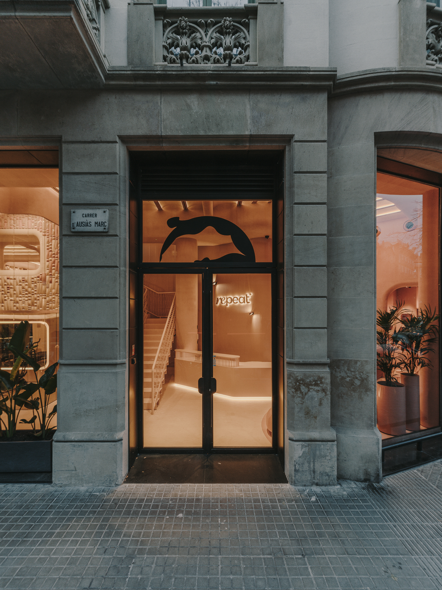 Street-level entrance with glass door framed by grey stone pilasters at dusk