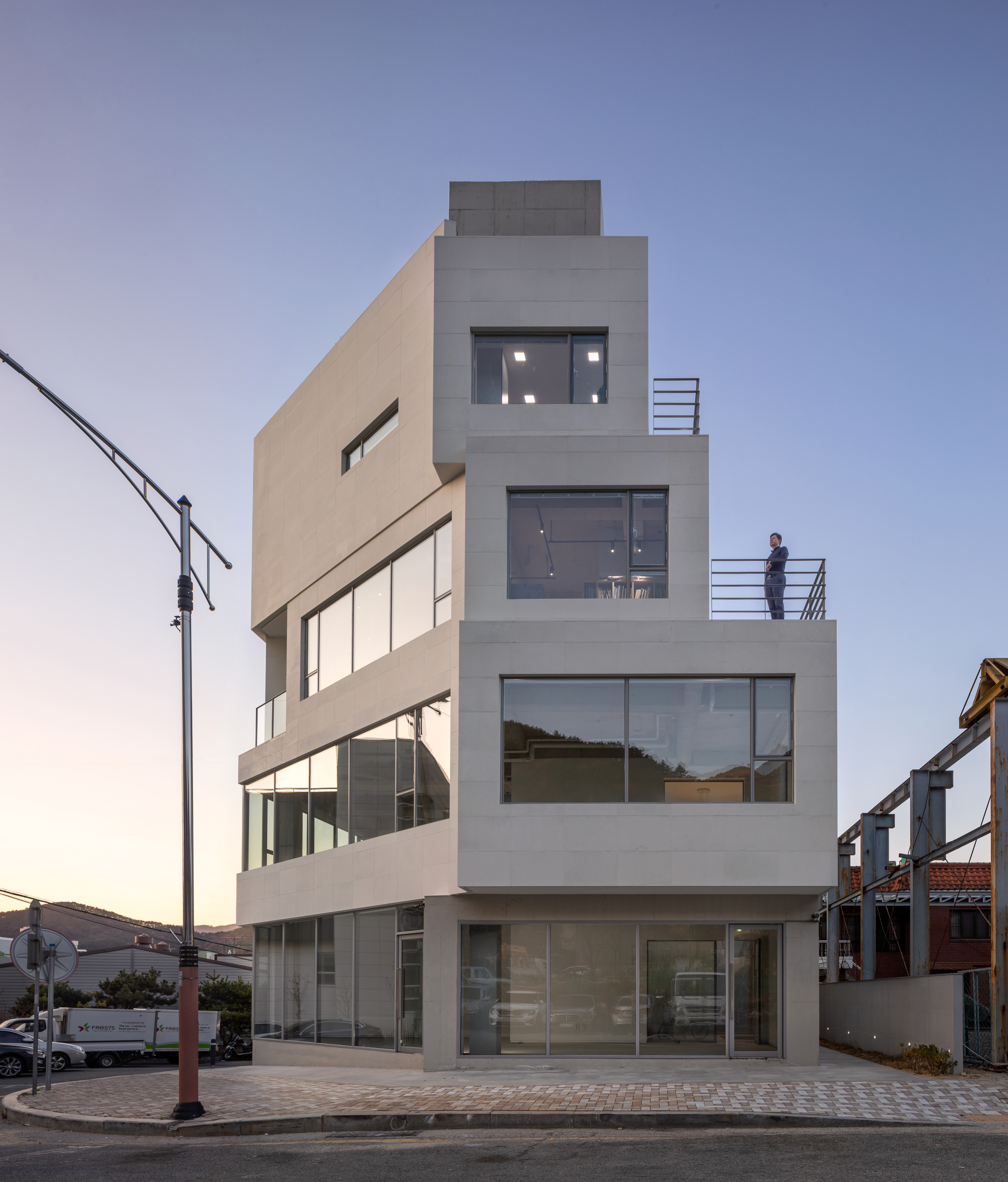 Four-story stucco facade with stacked terraces and full-height glazing at dusk