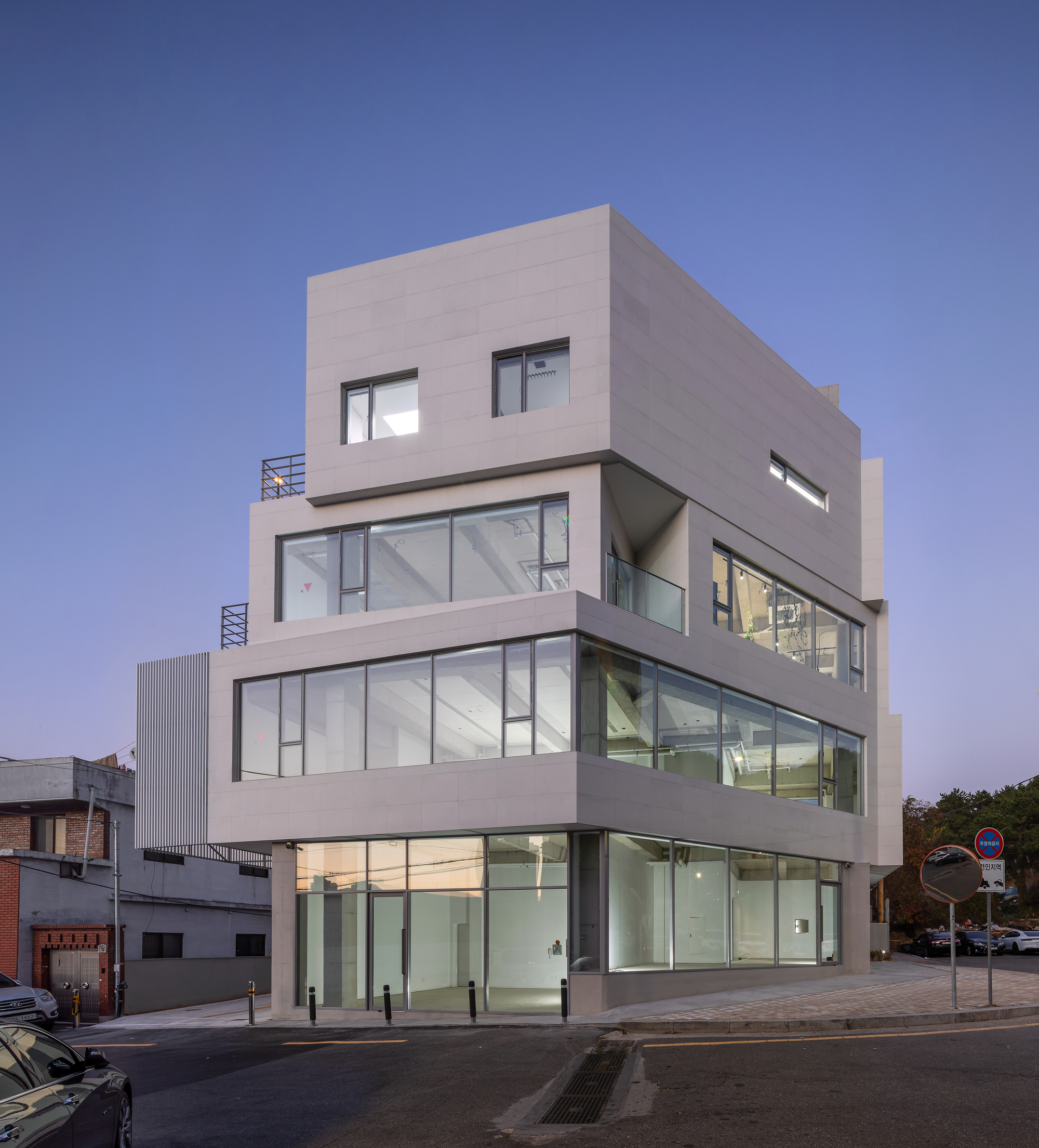 Street corner facade with offset floor plates and illuminated interiors at twilight
