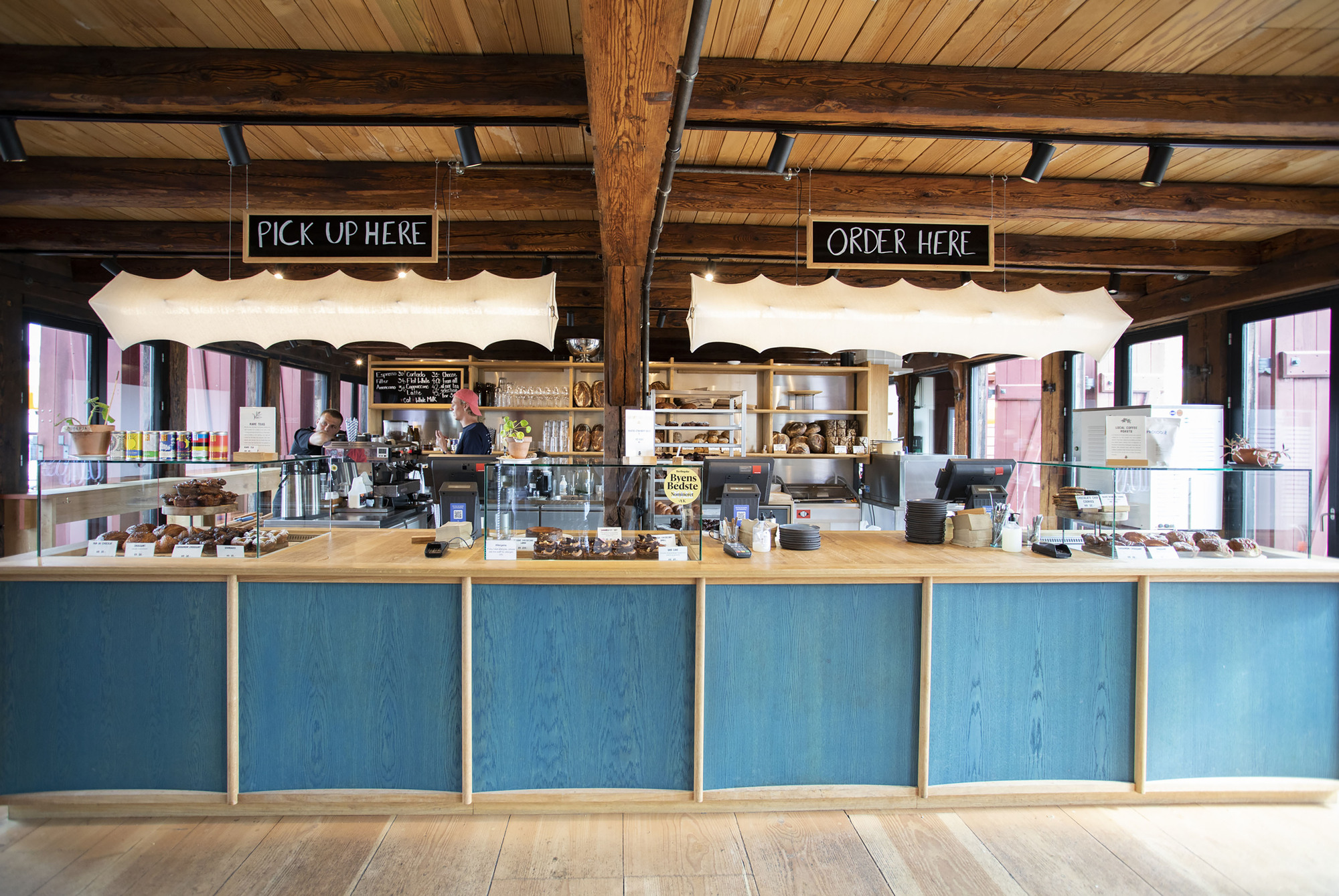 Service counter with blue-stained wood panels and timber ceiling beams with exposed steel brackets