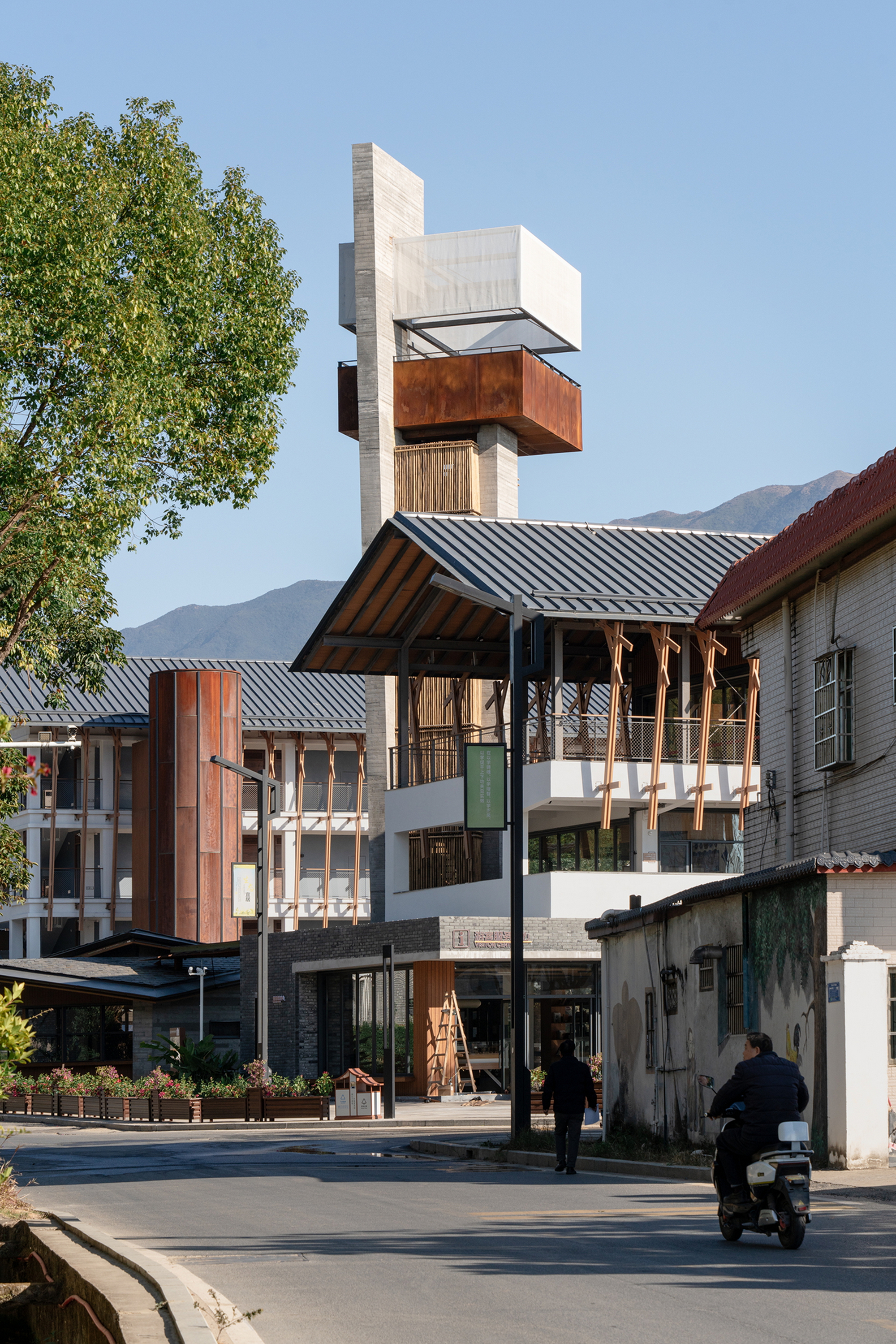 Street view of the concrete tower rising above tiled roofs with a motorcyclist passing