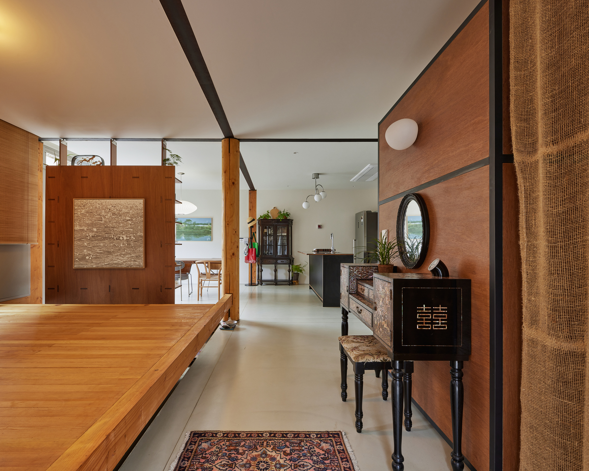 Open living space with timber-clad walls and polished concrete floor connecting kitchen to dining area