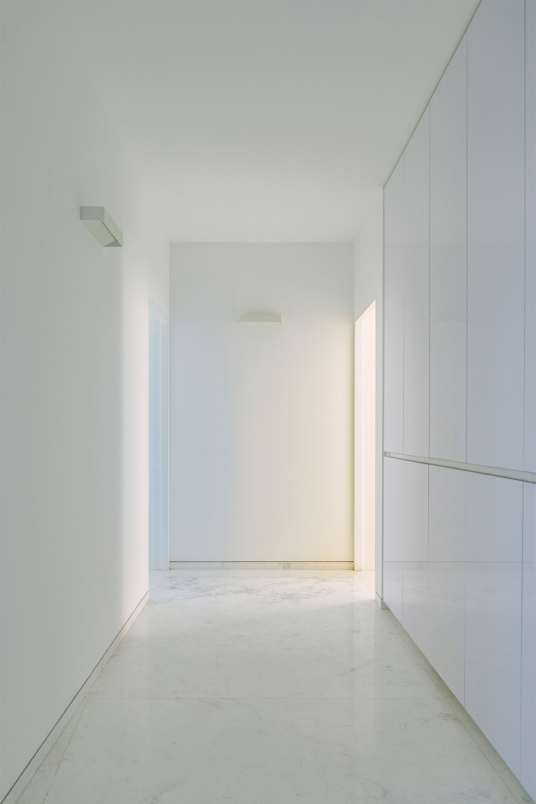 White corridor with built-in cabinetry and polished concrete floor under diffused natural light