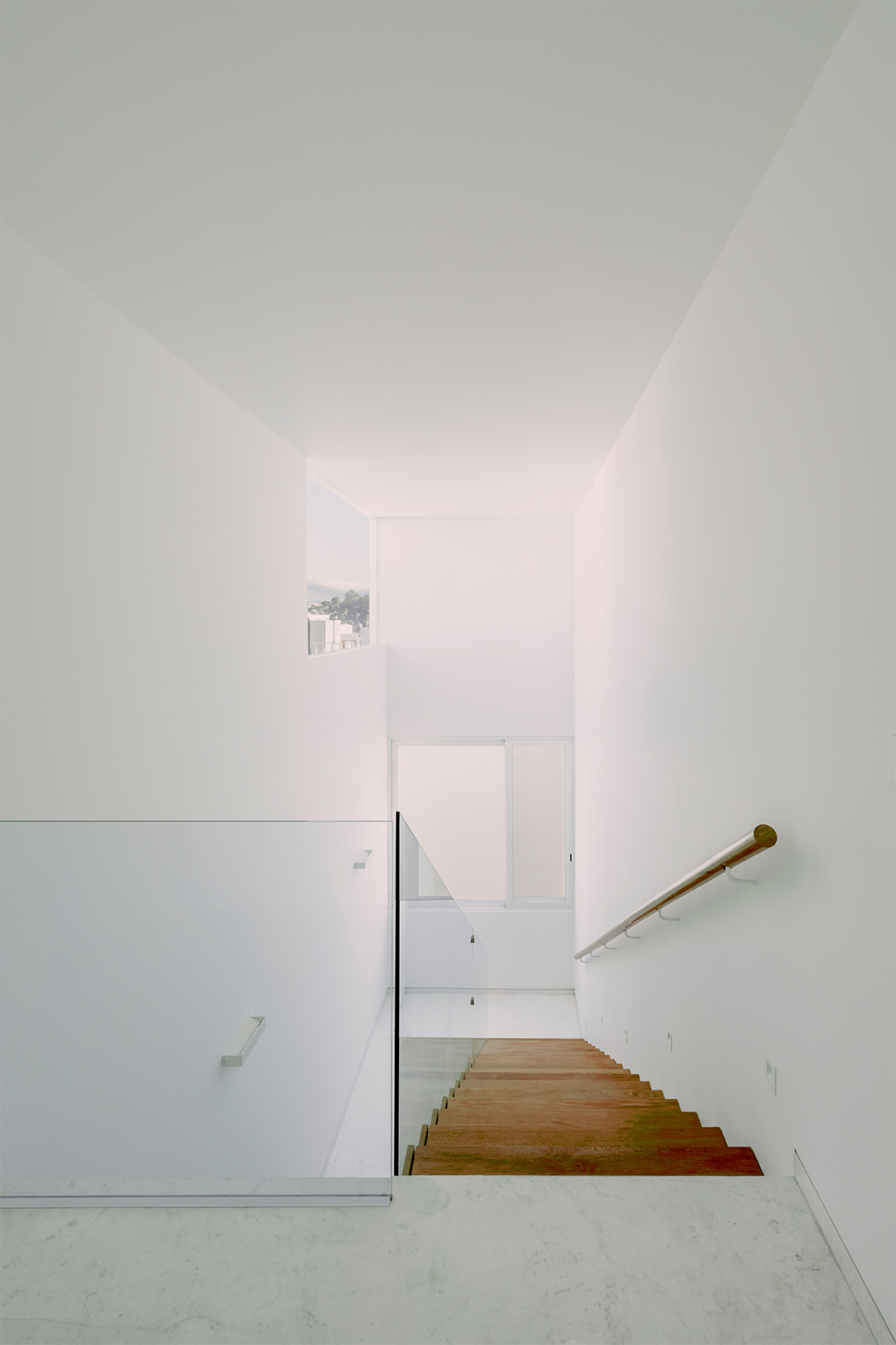 View down the timber staircase with wooden handrail and glimpse of window beyond